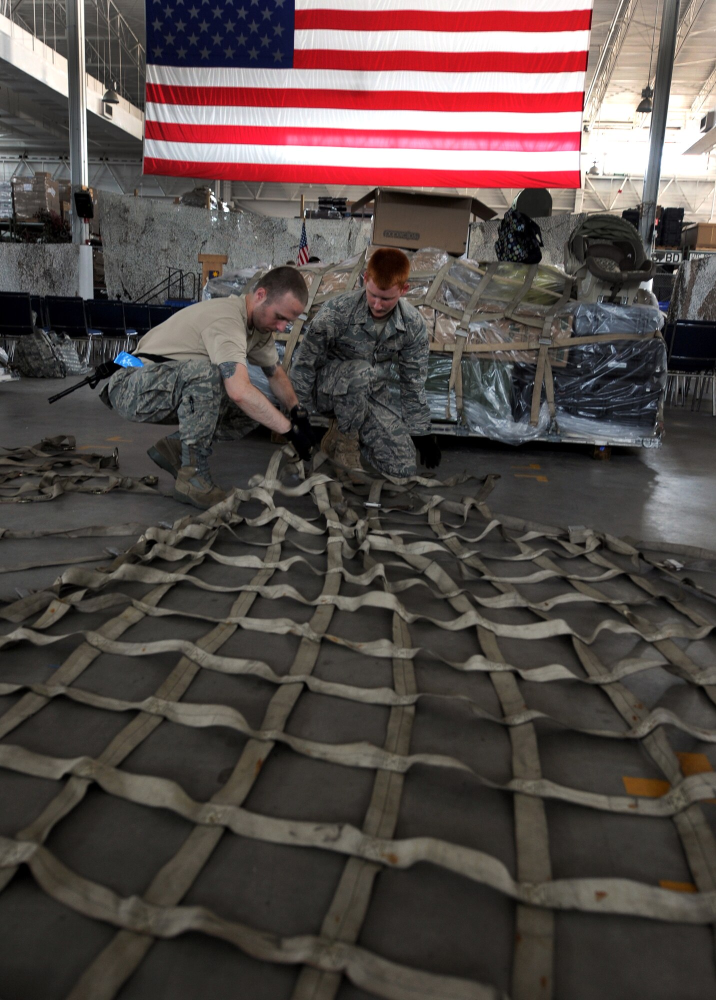 JOINT BASE MCGUIRE-DIX-LAKEHURST, N.J. – Staff Sgt. Tanner Krien, and Airman Sammie Koch, 819th Global Support Squadron air transportation specialists, inspect a cargo tie-down net at the 621 Contingency Response Wing’s Global Reach Deployment Center here June 2. The unit was preparing to deploy to Afghanistan in support of critical equipment logistics support. (U.S. Air Force photo/Tech. Sgt. Laura Deckman/released)