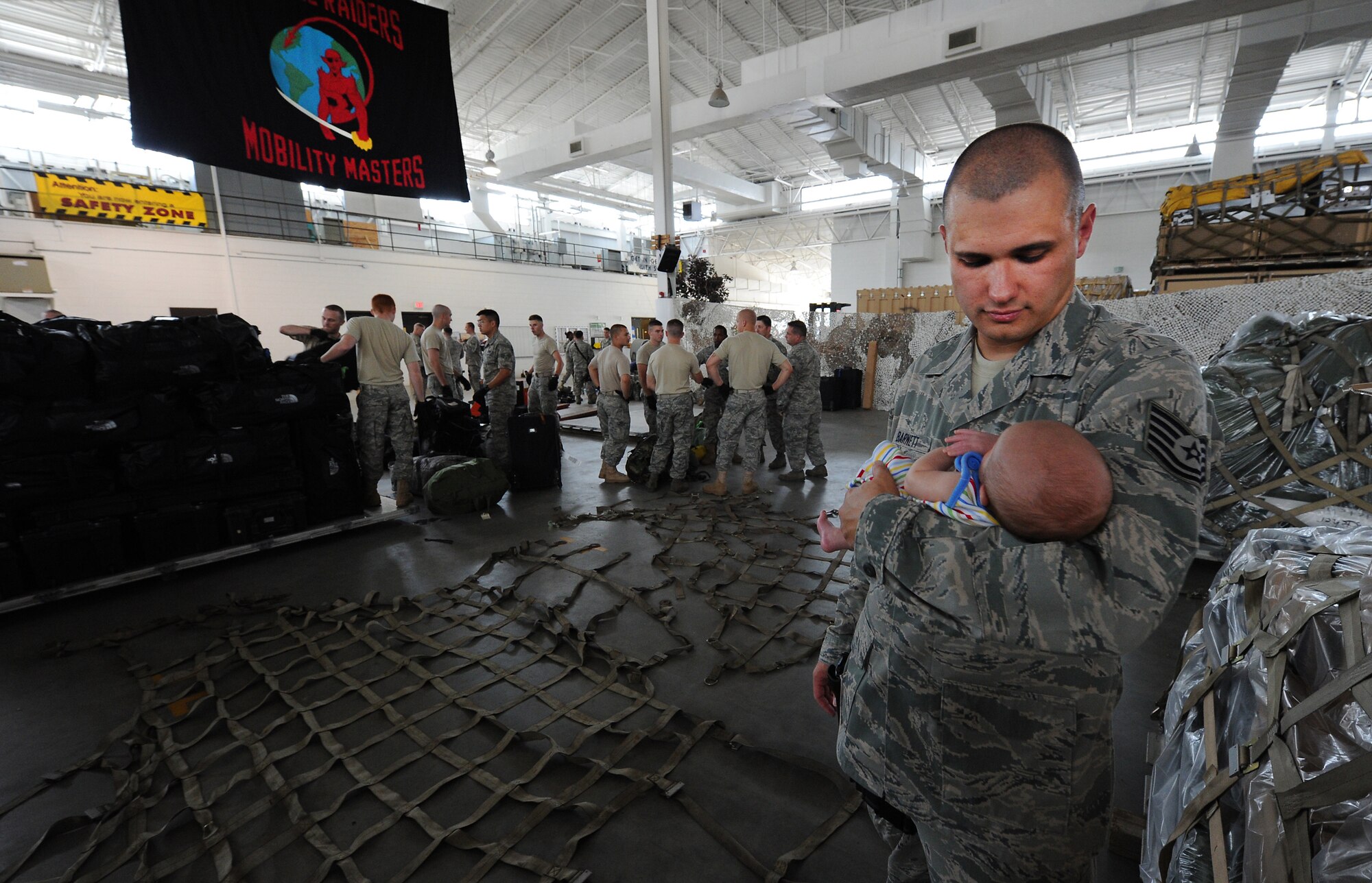 JOINT BASE MCGUIRE-DIX-LAKEHURST, N.J. – Tech. Sgt. Benjamin Barnett, 819th Global Support Squadron airfield operations technician, holds his six-week old boy Benjamin while his unit prepares to deploy to Afghanistan at the 621 Contingency Response Wing’s Global Reach Deployment Center here June 2.  Sergeant Barnett and his team were deploying to provide special cargo handling support for the Operation Enduring Freedom logistic surge. (U.S. Air Force photo/Tech. Sgt. Parker Gyokeres/released)