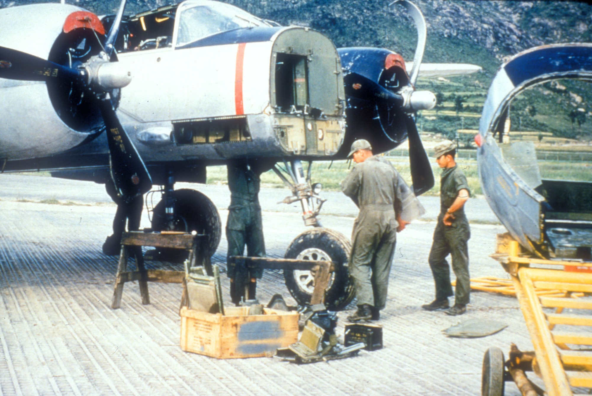 Mechanics repair damage from a rough landing. Note bent propellers. (U.S. Air Force photo)
