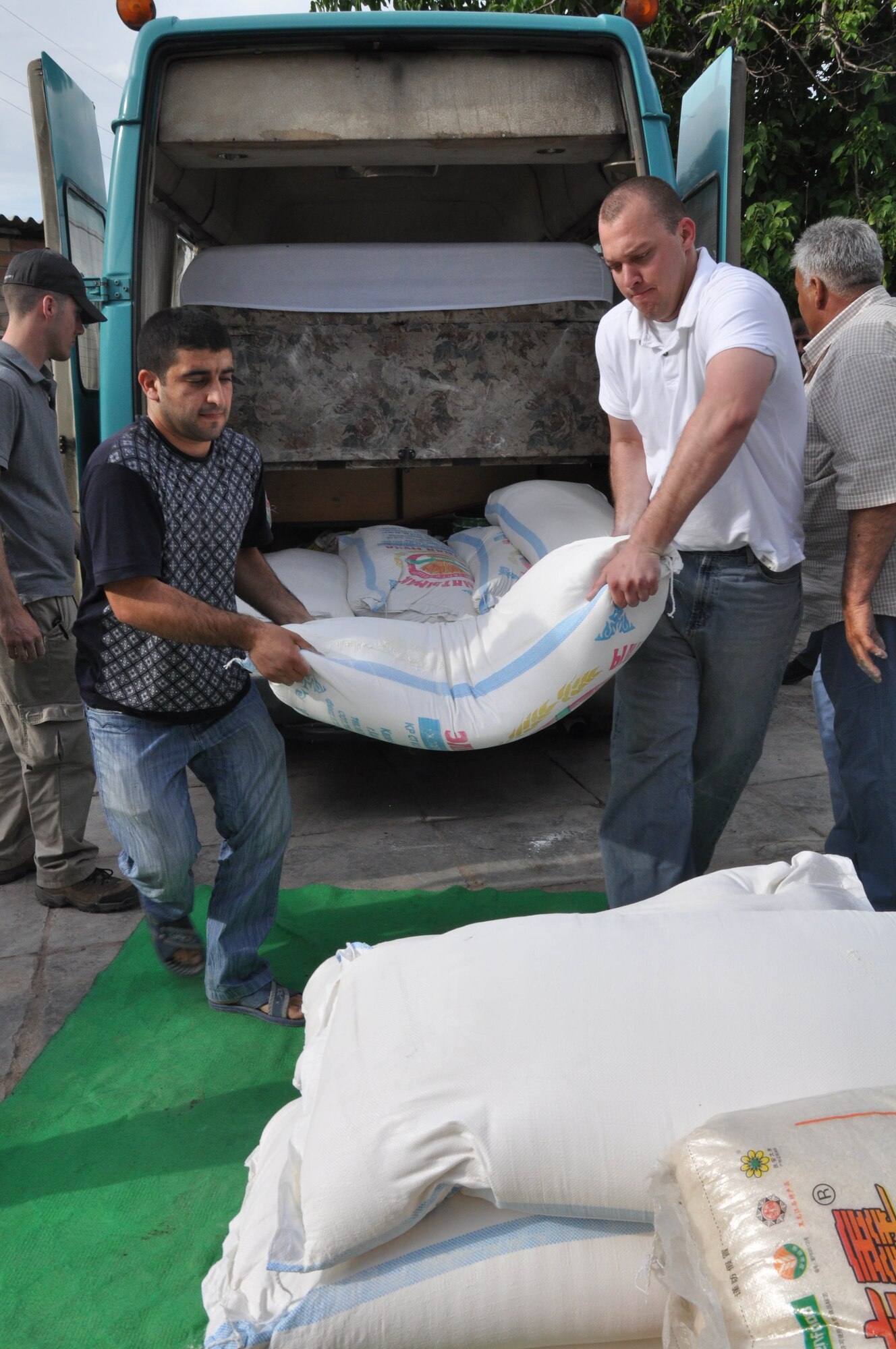 Staff Sgt. Jeremy McDonnell, an Airman from the Transit Center at Manas, Kyrgyzstan, helps a man from Maevka Village unload a van full of humanitarian assistance items June 7, 2010, for people of the village who lost all their household goods during the revolution in Kyrgyzstan April 7, 2010. (U.S. Air Force photo/Staff Sgt. Carolyn Viss)