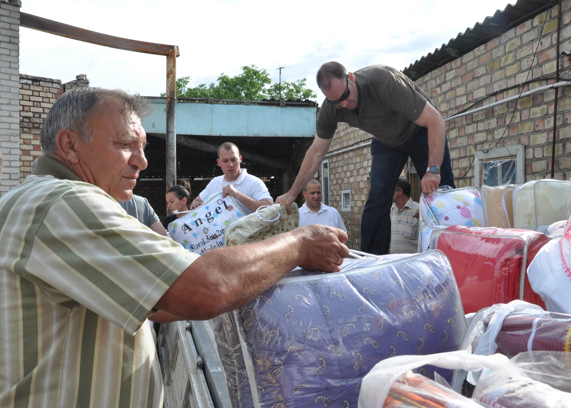 Airmen from the Transit Center at Manas, Kyrgyzstan, unload more than 60 blankets and sets of sheets and other humanitarian assistance items purchased on the local economy June 7, 2010, for people of Maevka Village who lost all their household goods during the revolution in Kyrgyzstan April 7, 2010. (U.S. Air Force photo/Staff Sgt. Carolyn Viss)
