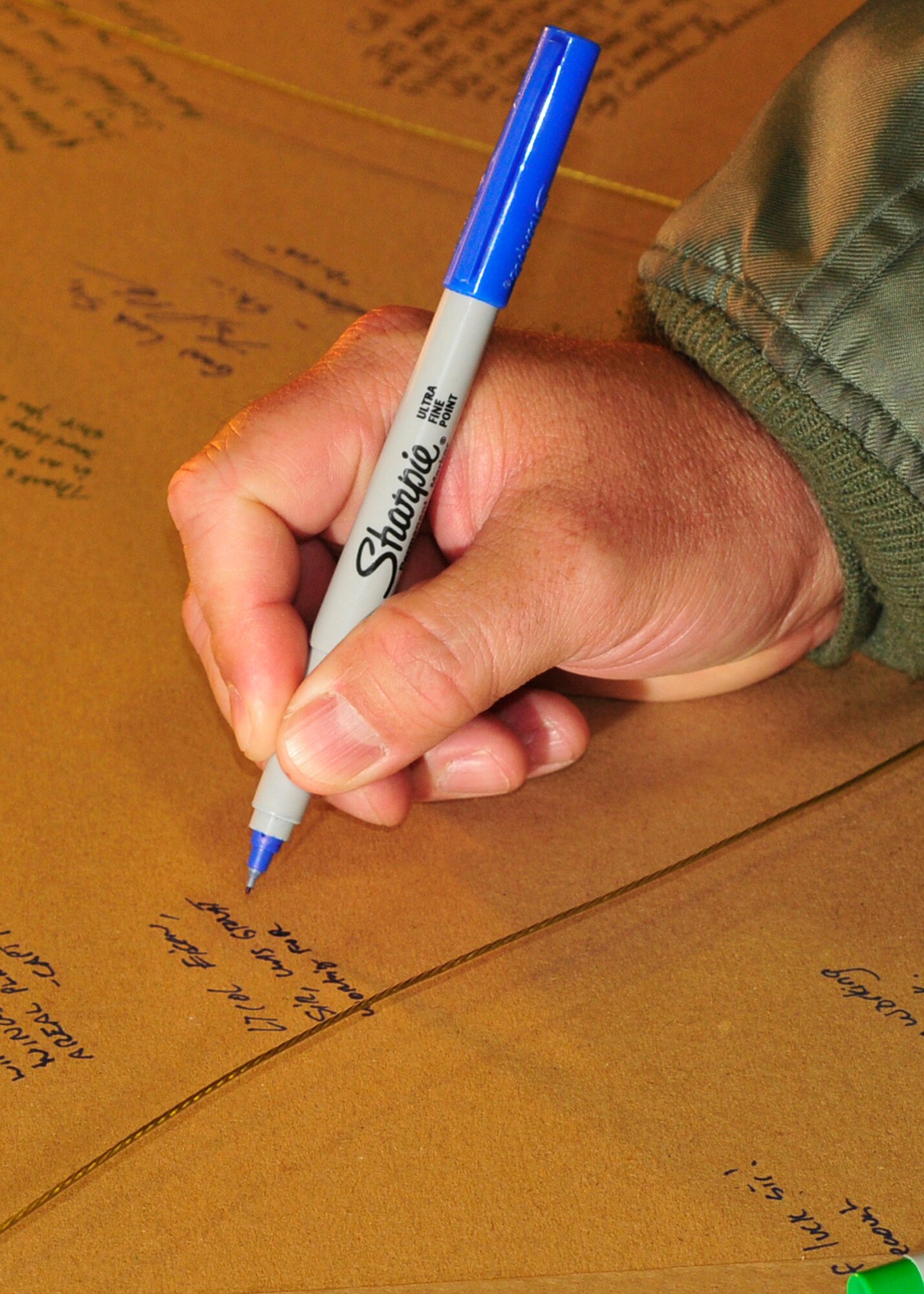 A recently deployed Airman signs a going away poster for Lt. Col. Eisen, 56th Rescue Squadron commander, at the Installation Deployment Readiness Cell at RAF Lakenheath, England, June 8. All the deployers lined up after an in-processing briefing to write a message to their departing commander while in-processing from a 90-day deployment. (U.S. Air Force photo/Airman 1st Class Eboni Knox)