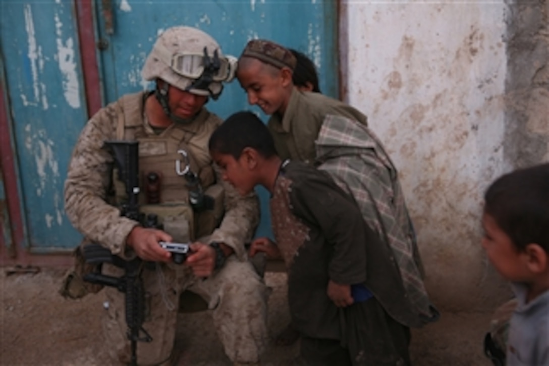U.S. Marine Corps Cpl. Hernandez (left) with Bravo Company, 1st Battalion, 6th Marine Regiment shows Afghan children a photograph he took in Marjah, Afghanistan, on Feb. 21, 2010.  The Marines were deployed in support of the International Security Assistance Force.  