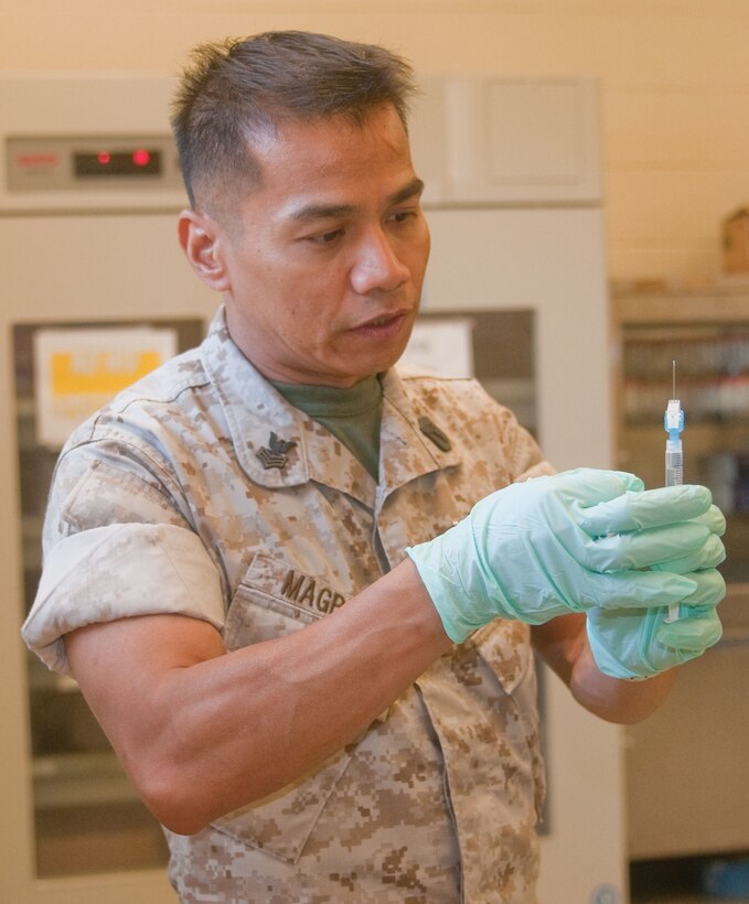 Petty Officer 1st Class Eduardo Magpayo, hospital corpsman, 1st Battalion, 3rd Marine Regiment, of San Diego, ensures there are no air bubbles in a syringe before administering a shot.