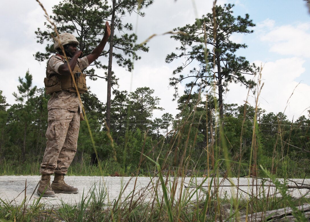 Cpl. Derrick Priest, a military working dog handler with Military Police Support Company, II Marine Expeditionary Force Headquarters Group, uses a radio to give his military working dog, Shandi, commands during road way training for smelling out explosives aboard Camp Lejeune, N.C., June 9, 2010.  While Shandi searched the road environment for explosive odors planted by the handlers, Priest radioed to her which directions to go and exactly what she needed to do.