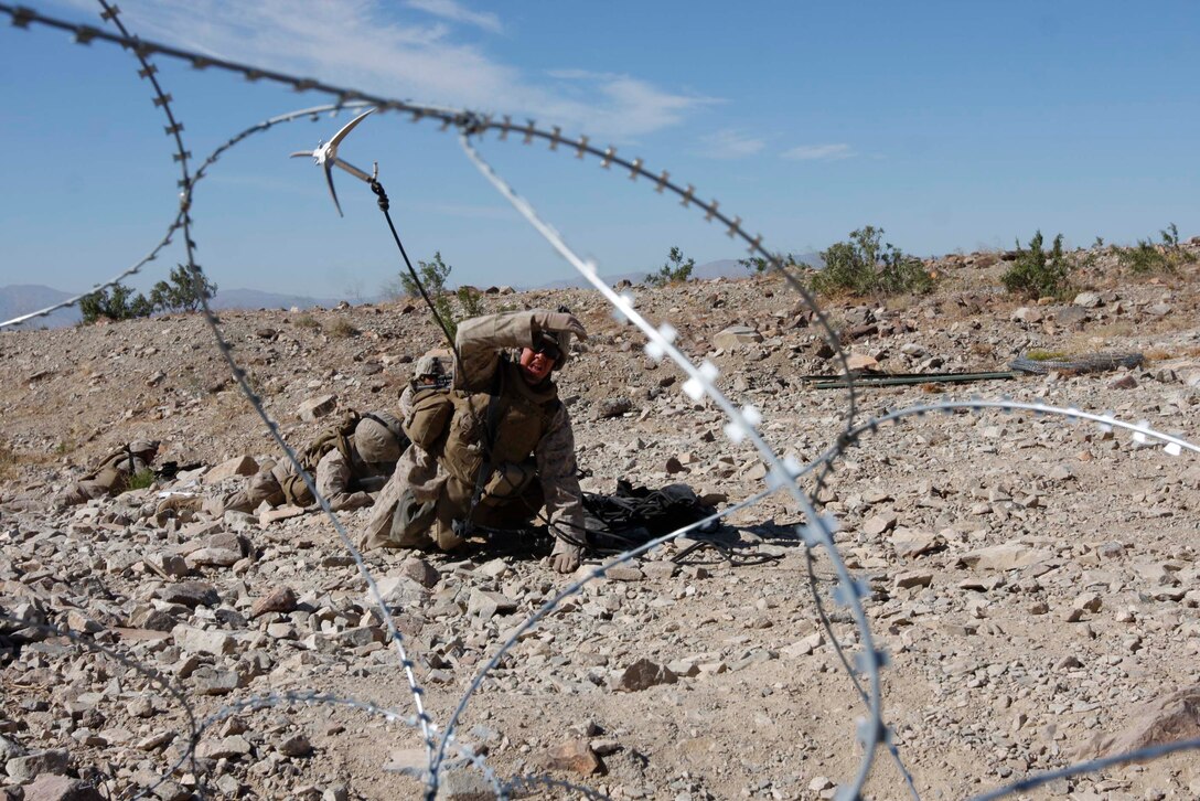 Private First Class Hayden Harmon, a rifleman with Company D, 3rd Light Armored Reconnaissance Battalion, throws a grappling hook to check barbed wire for boobytraps June 10 at Combat Center Range 410. The range helped the Marines operate outside of their light armored vehicles and clear trenches.