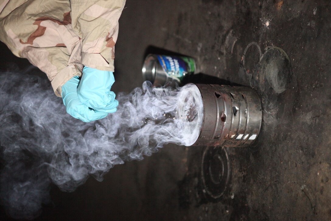Staff Sergeant Grace E. Kingstad, a Chemical, Biological, Radiological, and Nuclear defense specialist with 26th Marine Expeditionary Unit, opens a CS gas capsule in order to start the gas chamber during Realistic Urban Training (RUT) aboard Fort A.P. Hill, Va., June 10, 2010. During the 18-day training evolution, the MEU will conduct several urban training exercises as part of its pre-deployment training. The urban environment is among the most challenging tactical environments MEU Marines may face. 26th MEU is scheduled to deploy later this fall.