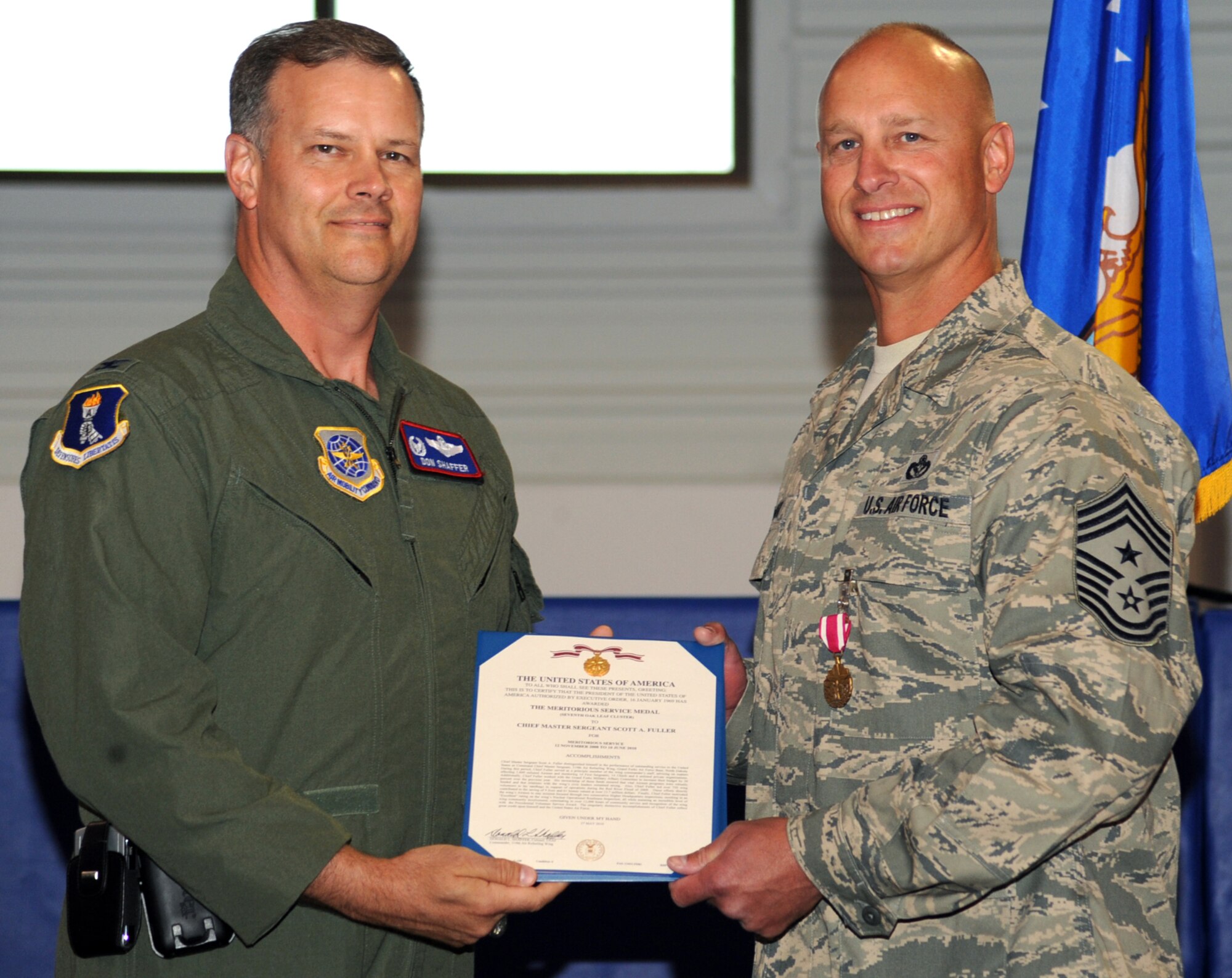 Col. Don Shaffer, Commander, 319th Air Refueling Wing and Chief Master Sergeant Scott Fuller, Command Chief, 319 ARW (from left to right), pose for a picture after Colonel Shaffer presented Chief Fuller with a Meritorious Service Medal, seventh oak leaf cluster, for his time spent here. Chief Fuller will deploy down range as a command chief for a forward operating base. (U.S. Air Force photo by Airman 1st Class Amber Price)