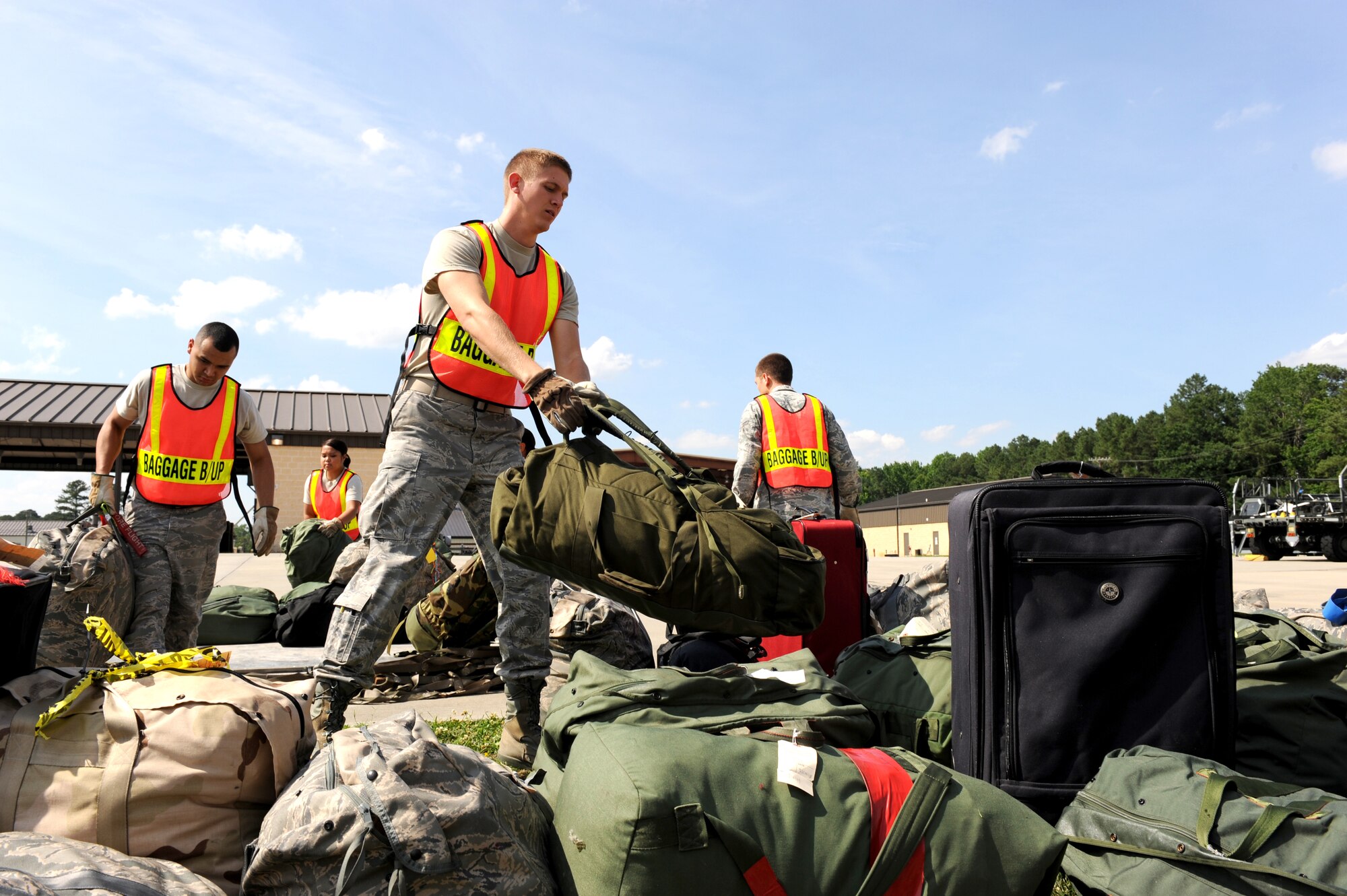 SEYMOUR JOHNSON AIR FORCE BASE, N.C. -- Airman 1st Class Brandon Holliday adds another bag of deployment gear to the pile outside the Personnel Deployment Facility here June 8, 2010. Augmentees such as Airman Holliday build cargo pallets, process cargo and provide security for the PDF. An avionics sensors technician assigned to the 4th Component Maintenance Squadron, Airman Holliday hails from Little Rock, Ark.  (U.S. Air Force photo/1st Lt. Matt Schroff)