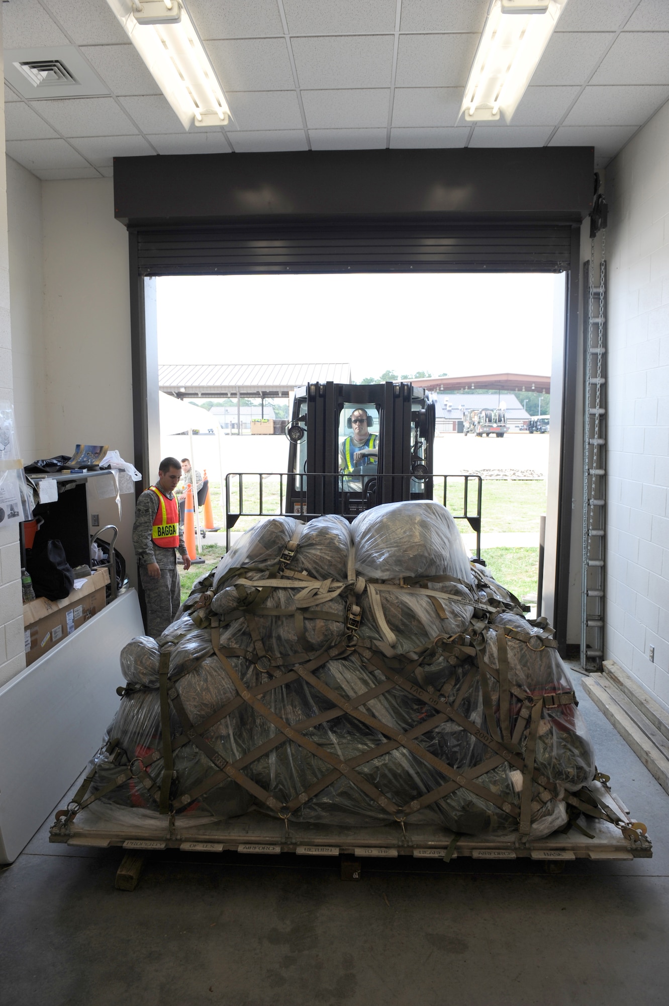 SEYMOUR JOHNSON AIR FORCE BASE, N.C. -- Airman 1st Class David Rankin marshals a forklift driven by Staff Sgt. Byron Faidherbe as a pallet is removed from the Personnel Deployment Facility here June 8, 2010. Airmen place cargo, such as this load of mobility bags, on standard-sized pallets, which are covered in plastic and secured with straps before being weighed, inspected and loaded onto aircraft.  Marshallers ensure safe movement of pallets by directing heavy equipment operators with verbal and hand signals. Although assigned as an augmentee during the exercise, Airman Rankin is a fuels maintainer for the 4th Component Maintenance Squadron and hails from Waterford, Ohio. Sergeant Faidherbe is the 4th Civil Engineer Squadron training manager, and is from Linton, Ind.  (U.S. Air Force photo/1st Lt. Matt Schroff)