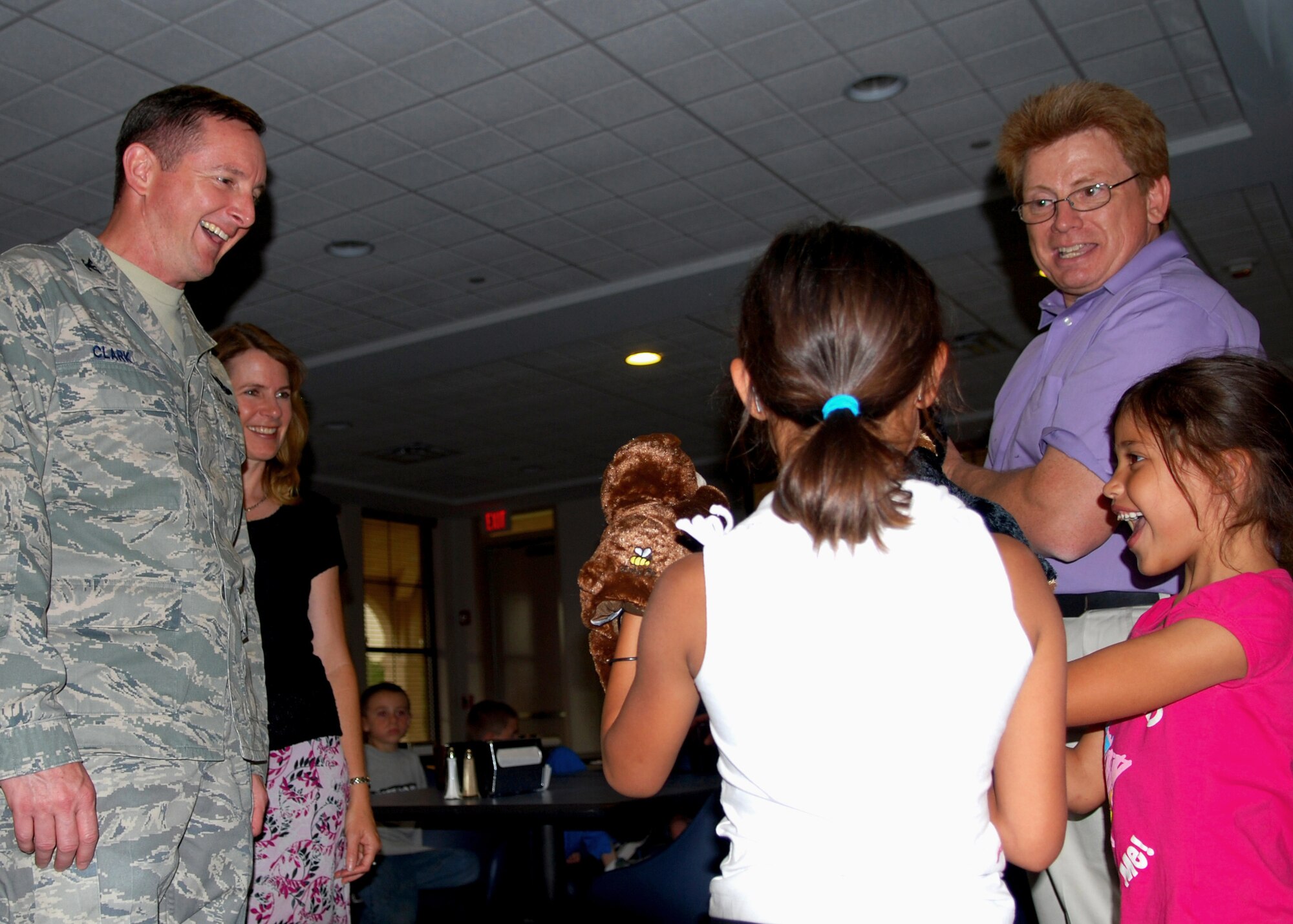 Colonel Stephen Clark, 27th Special Operations Wing commander, smiles as children enjoy the puppets provided to them by John Fondrick from the Airman and Family Readiness Center during the Deployed Remote Family Meal June 8. This  quarterly  dinner at the Pecos Trail Dining Facility is hosted by A&FRC, and provides families whose Airmen are deployed the opportunity to socialize with others. (U.S. Air Force Photo by Master Sgt. Carlotta Holley)