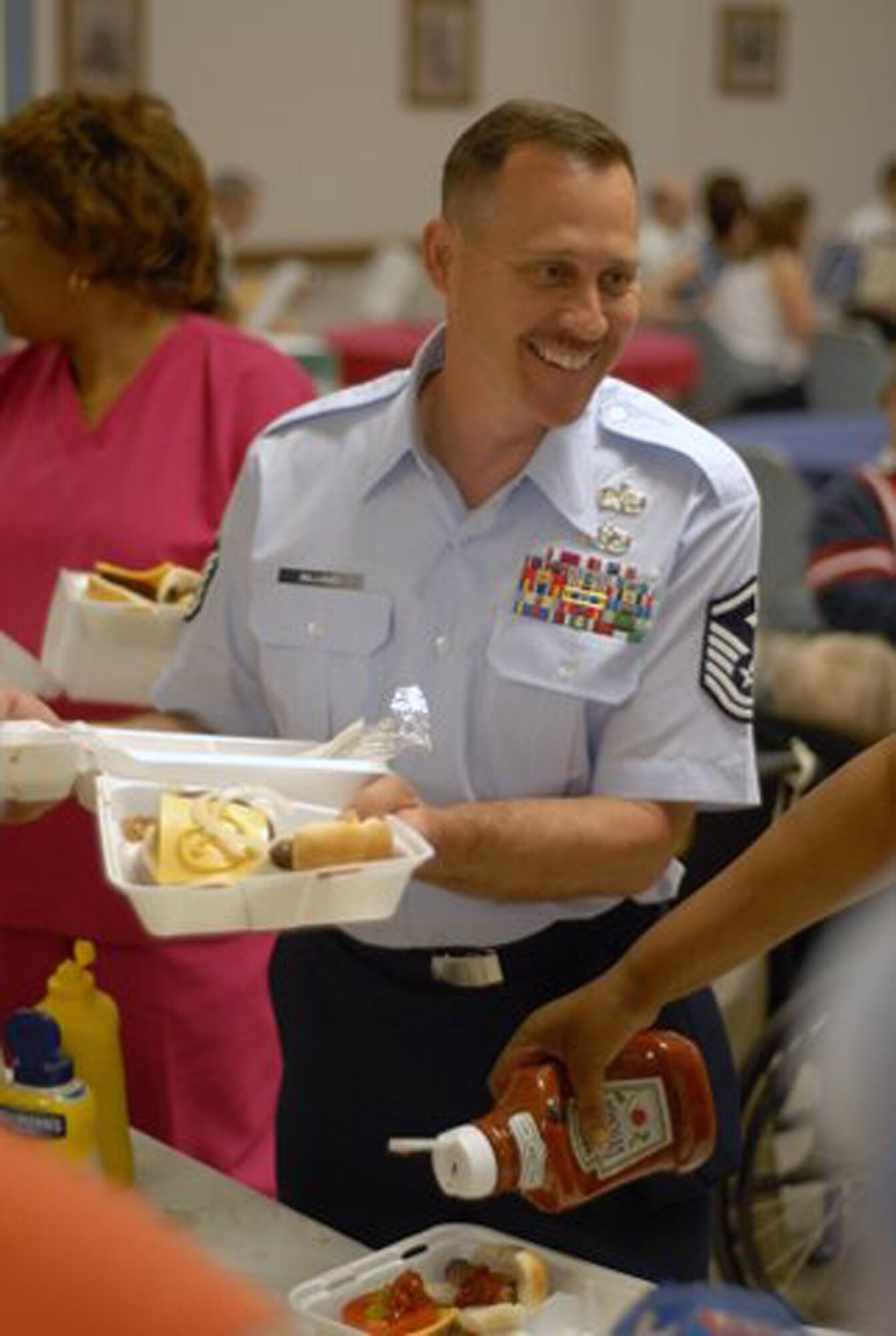 WRIGHT-PATTERSON AIR FORCE BASE, Ohio – Master Sgt. Chris Williams, first sergeant for the 445th Mission Support Flight and 445th Services Flight, carries two lunches for residents during the annual VA picnic June 5 at the Veterans Affairs Medical Center in Dayton, Ohio.  Reservists from the 445th Airlift Wing support the event every year, working with the Air Force Sergeants Association Kittyhawk Chapter 751 and the Air Force Association to support the VA residents.  (U.S. Air Force photo/Master Sgt. Charlie Miller)