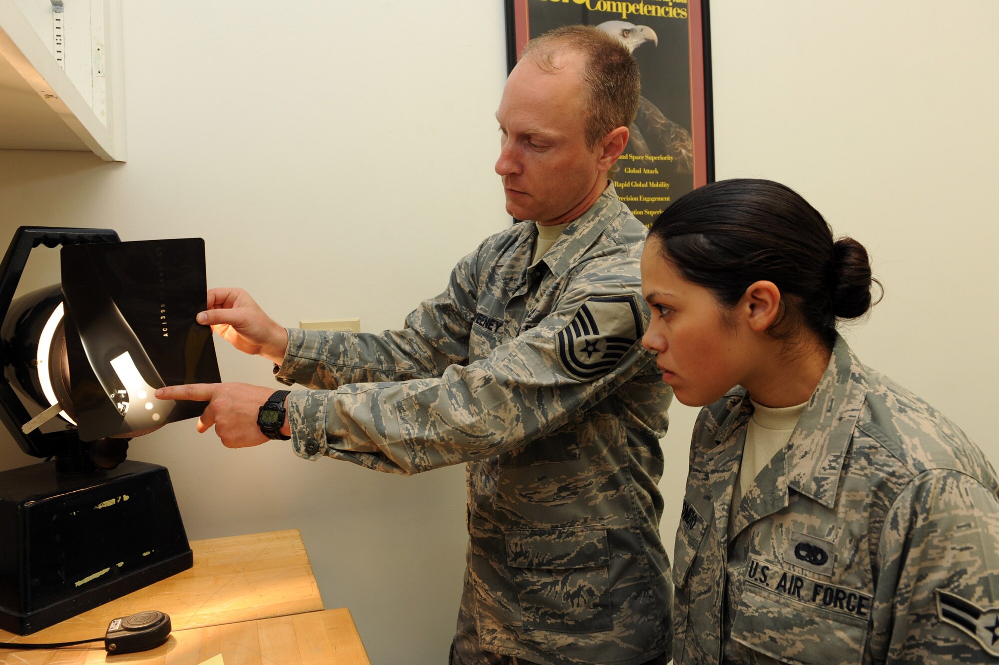 Master Sgt. Michael Sweeney, 19th Equipment Maintenance Squadron non-destructive inspection section chief, shows Airman 1st Class Veronica Romero, 19th Equipment Maintenance Squadron non-destructive inspection apprentice, June 8 how to identify foreign objects on X-rays of damaged equipment at the base non-destructive inspection lab. (U.S. Air Force photo by Senior Airman Ethan Morgan)