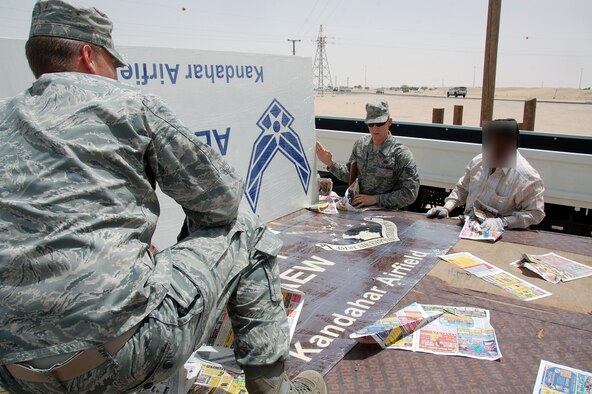 U.S. Air Force Staff Sgt. Joseph Hoh, center, 386th Expeditionary Contracting Squadron contingency contracting officer, reviews signs created through a civilian company before signing for them June 9, 2010 near an undisclosed air base in Southwest Asia. (U.S. Air Force photo illustration by Tech. Sgt. Lindsey Maurice/Released)