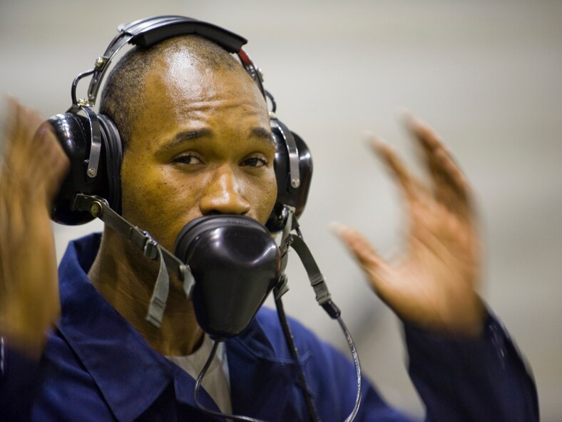 MISAWA AIR BASE, Japan -- Staff Sgt. Donterrio Erby, 35th Maintenance Squadron test-cell technician, signals to be cautious of loud noise during the beginning stages of an engine run May 3 at the Hush House. During testing, the engine can produce about 29,000 pounds of thrust and burn more than 2,000 gallons of fuel. (U.S. Air Force photo/Senior Airman Jamal D. Sutter)