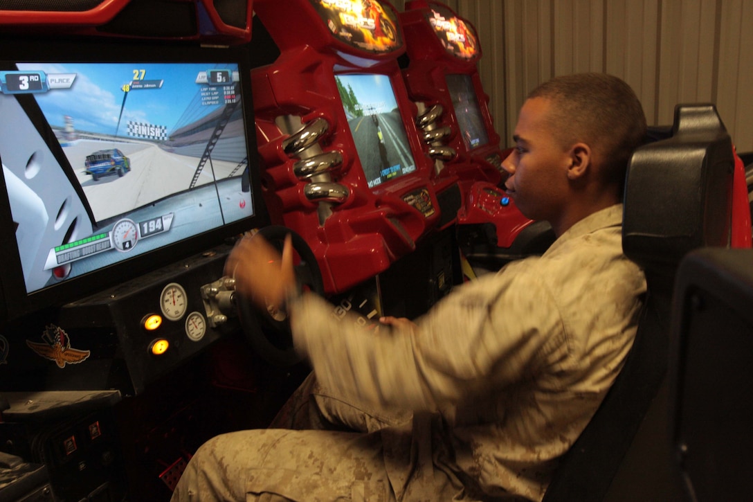 Lance Cpl. Hector Ortiz, a rifleman with 1st Battalion, 8th Marine Regiment, enjoys a racing game during his time off at the Warriors Club June 11.::r::::n::