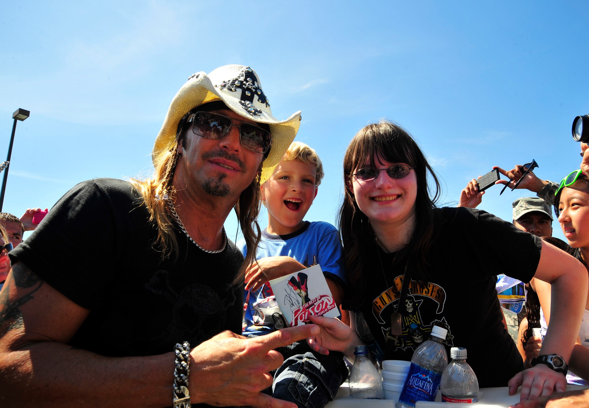 Bret Michaels poses for a photo with from left, Jonthan and Lauren MacKay, ages 5 and 15 respectively, at the Hurlburt Field's Base Exchange parking lot during his visit to Hurlburt Field, Fla., June 11, 2010.  Jonthan and Lauren are the children of Master Sgt. Scott MacKay, NCOIC of the 1st Special Operations Wing Public Affairs Office.(DoD photo by U. S. Air Force Senior Airman Sheila deVera/Released)