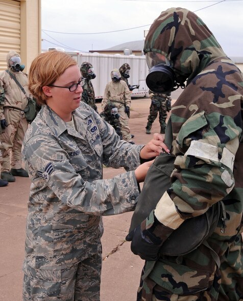 BARKSDALE AIR FORCE BASE, La. ? Senior Airman Laura Heineman, 2d Civil Engineering Squadron emergency management journeyman, assists Tech. Sgt. Joseph Williamson, 26th operational Weather Squadron weather forecaster, with his gas mask carrier during the emergency management training held June 6. This training covers a wide variety of threats that may potentially occur on Air Force installations. (U.S. Air Force photo by Senior Airman La?Shanette V. Garrett)(RELEASED)