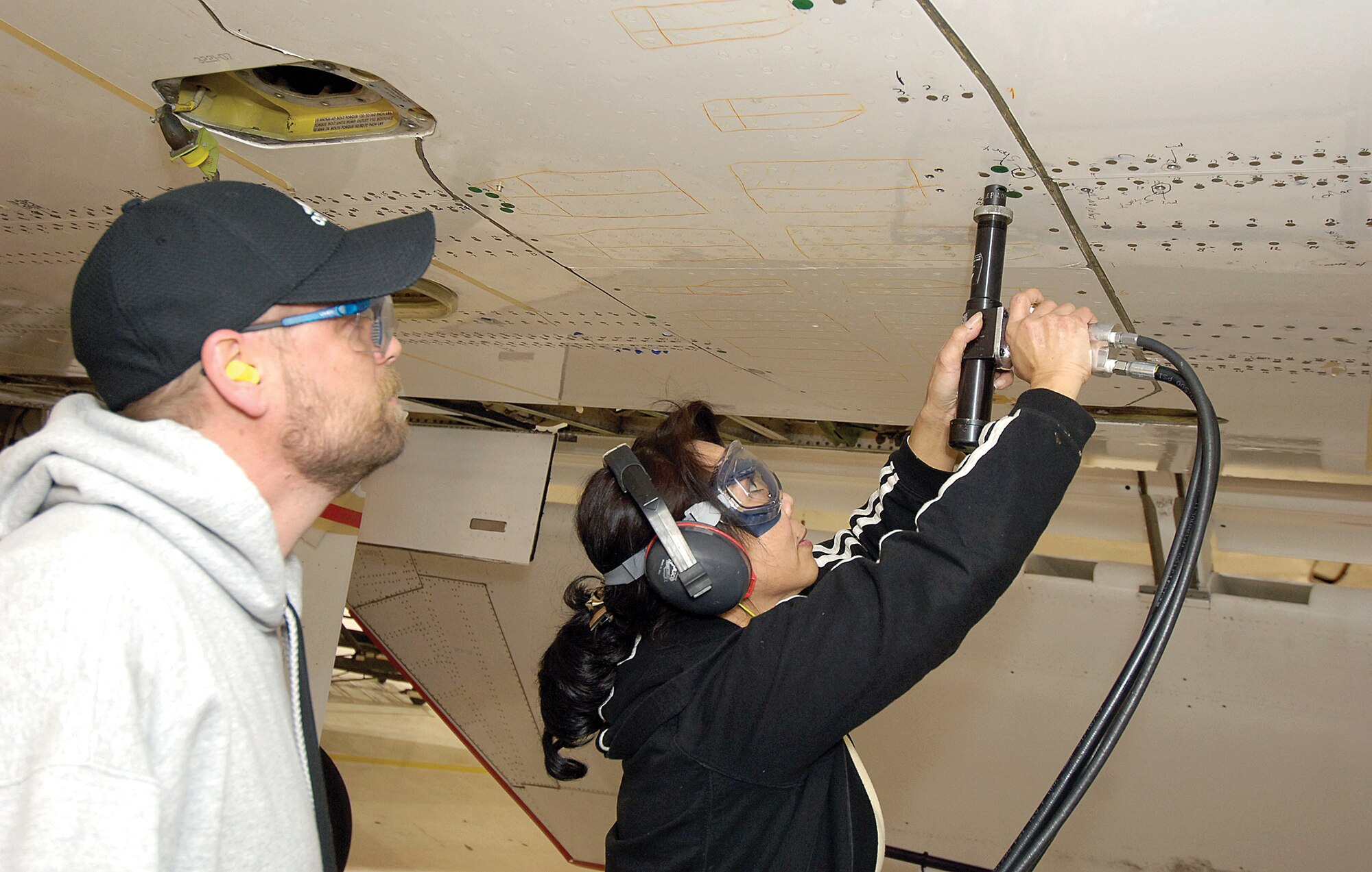 Sheet metal mechanics Eric Dart and Kimberly Nguyen are part of a Tinker team modifying Navy E-6 aircraft by strengthening the wings to better endure stress from the angle the jet assumes during missions.(Air Force photos by Margo Wright)