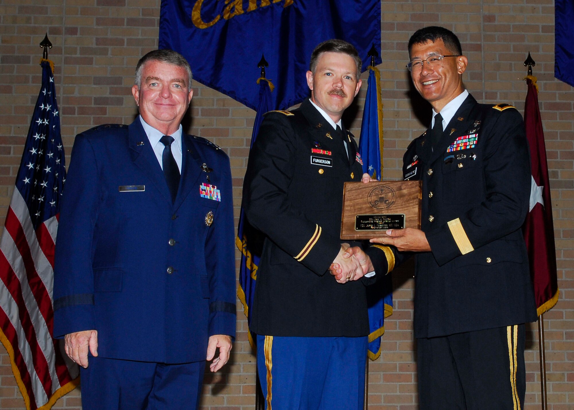 Col. James L. Furgerson, cardiovascular disease fellowship program director, Brooke Army Medical Center, Ft. Sam Houston, Texas, accepts the Col. John D. Roscelli Award from BAMC Commander Brig. Gen. Joseph Caravalho (right) and 59th Medical Wing Commander Maj. Gen. Thomas Travis (left) during the San Antonio Uniformed Services Health Education Consortium annual awards ceremony June 4 in the University of Texas Health Science Center at San Antonio auditorium, San Antonio, Texas. The award recognizes an outstanding program director. (U.S. Air Force photo by Alan Boedeker)