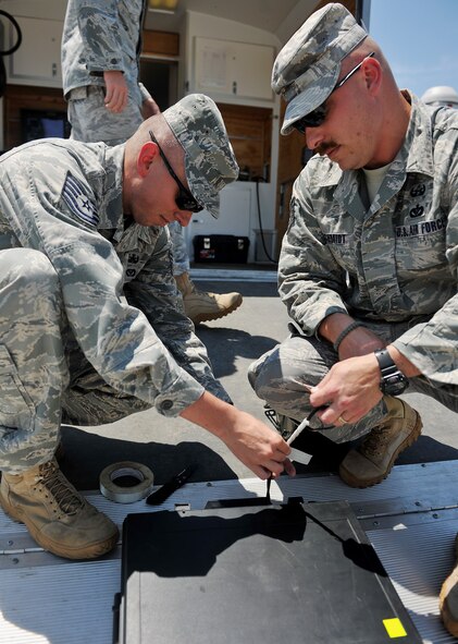 MOODY AIR FORCE BASE, Ga. -- Tech. Sgt. Richard Schmidt and Stanley Thompson, 23rd Civil Engineering Squadron explosive ordnance disposal craftsman and journeyman, attach fire wire to a boot banger explosive at a multi-agency exercise at the Valdosta Airport, Valdosta, Ga.  June 9.  The boot banger is an explosive that uses water to disrupt other ordnances. (U.S. Air Force photo by Airman 1st Class Joshua Green/RELEASED)  
