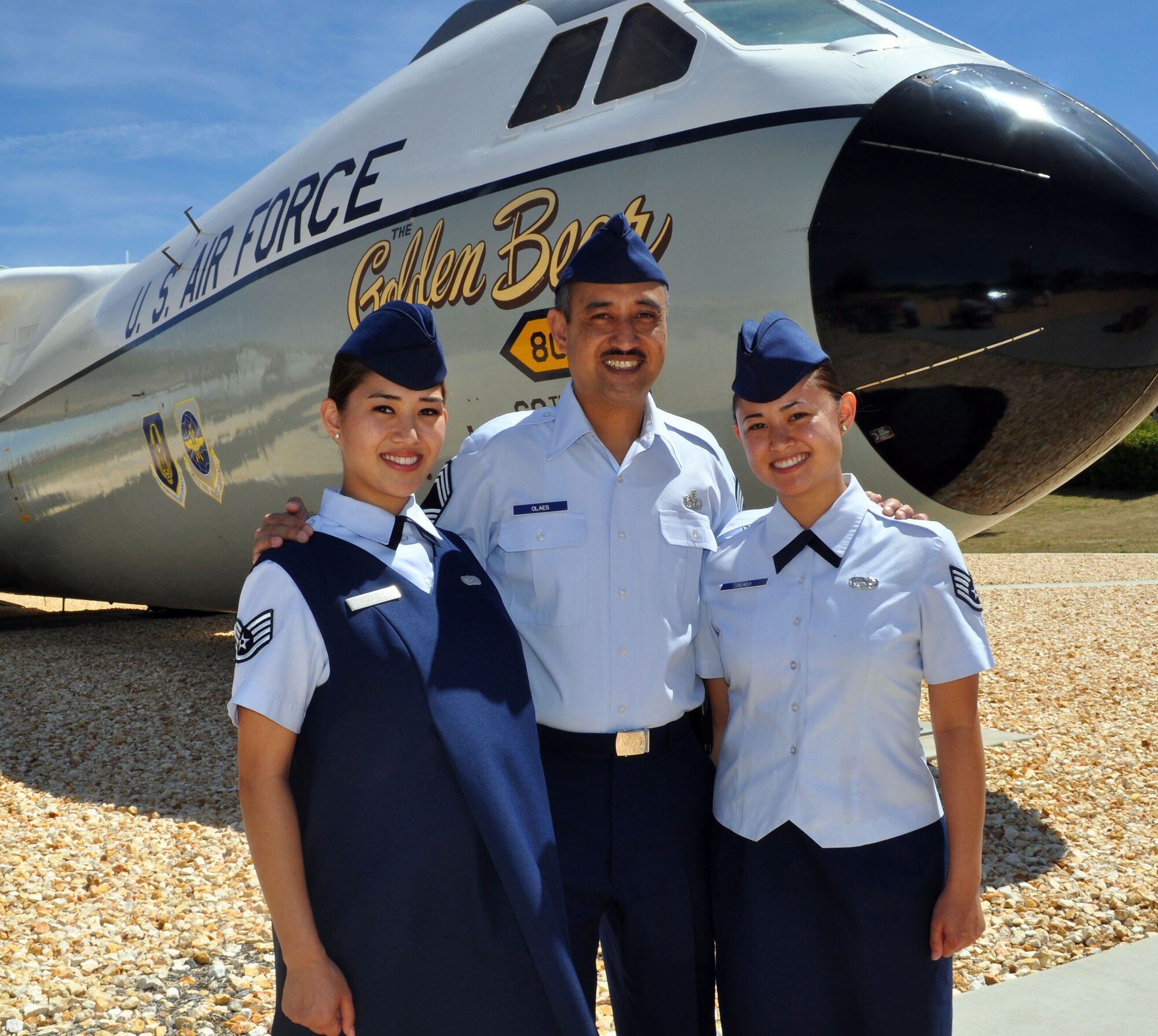 TRAVIS AIR FORCE BASE, Calif. -- Sisters and both staff sergeants, Josephine Tunnell, left, and Mary Kathleen Olaes, right, pose in front of the "Golden Bear" with their father, Chief Master Sgt. Rogelio Olaes, after their re-enlistment ceremony June 6, 2010. Josephine is assigned to the 349th Memorial Affairs Squadron and Mary Kathleen is assigned to the 45th Aerial Port Squadron. The Chief is a career maintainer, and assigned to the 570th Contingency Response Group. Josephine and her husband, Peter, a former Airman, are expecting their first child, a boy, Aug. 1. The chief departed June 7 for a one-year remote tour of duty to Kunsan Air Base, Korea. (U.S. Air Force photo/Senior Master Sgt. Ellen L. Hatfield)