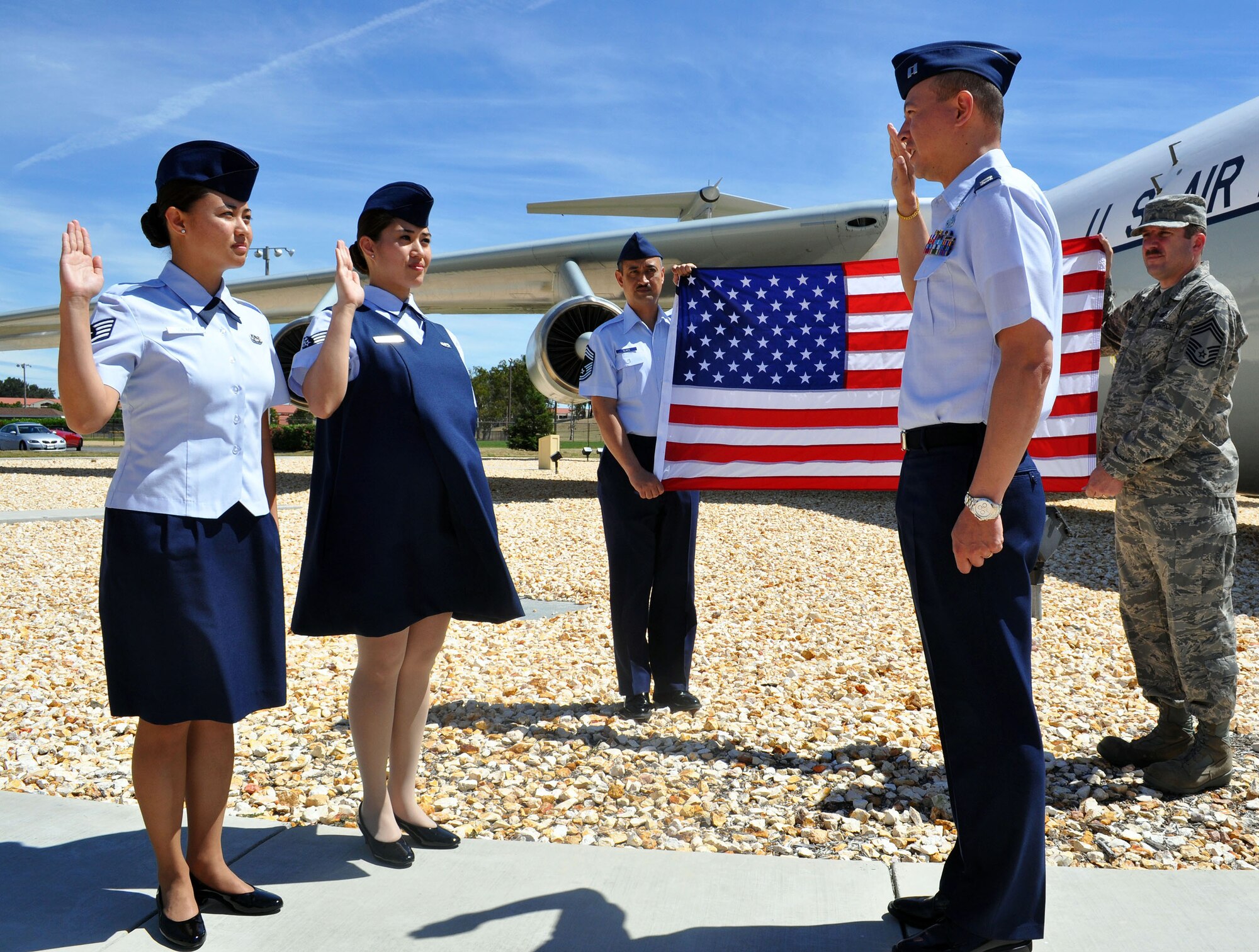 TRAVIS AIR FORCE BASE, Calif. -- The Olaes family makes the Air Force, and re-enlistment, a family affair. From the left: Staff Sgts. Mary Kathleen Olaes and Josephine (Olaes) Tunnell re-enlist in the 349th Air Mobility Wing for another six years. Holding the flag in blue is their dad, Chief Master Sgt. Rogelio Olaes, a career maintainer assigned to the 570th Contingency Response Group, 615th Contingency Response Wing. Administering the oath of enlistment is Capt. George Carter, known as "Uncle George" to the sisters. The captain is assigned to the 15th AMOS. (U.S. Air Force photo/Senior Master Sgt. Ellen L. Hatfield)
