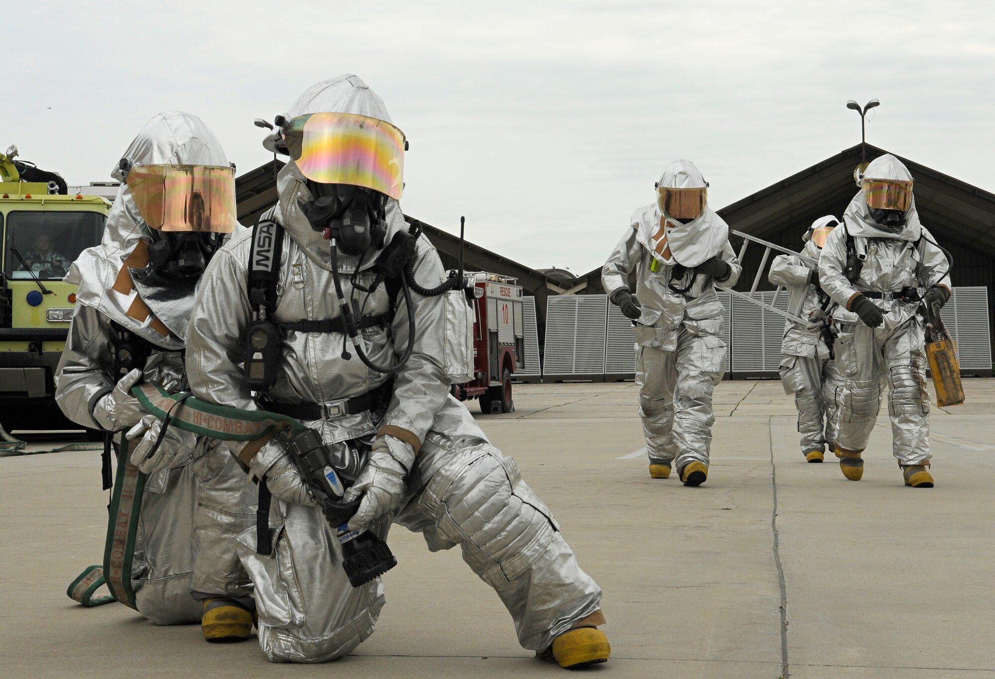 SPANGDAHLEM AIR BASE, Germany – Firefighters from the 52nd Civil Engineer Squadron stand by with a hose as three members carry tools used to extract a pilot from an aircraft during a demonstration here June 10. The fire department performed an exercise to show their capabilities to visiting fire and emergency responders from Germany, Bulgaria and Romania. (U.S. Air Force photo/Senior Airman Benjamin Wilson)