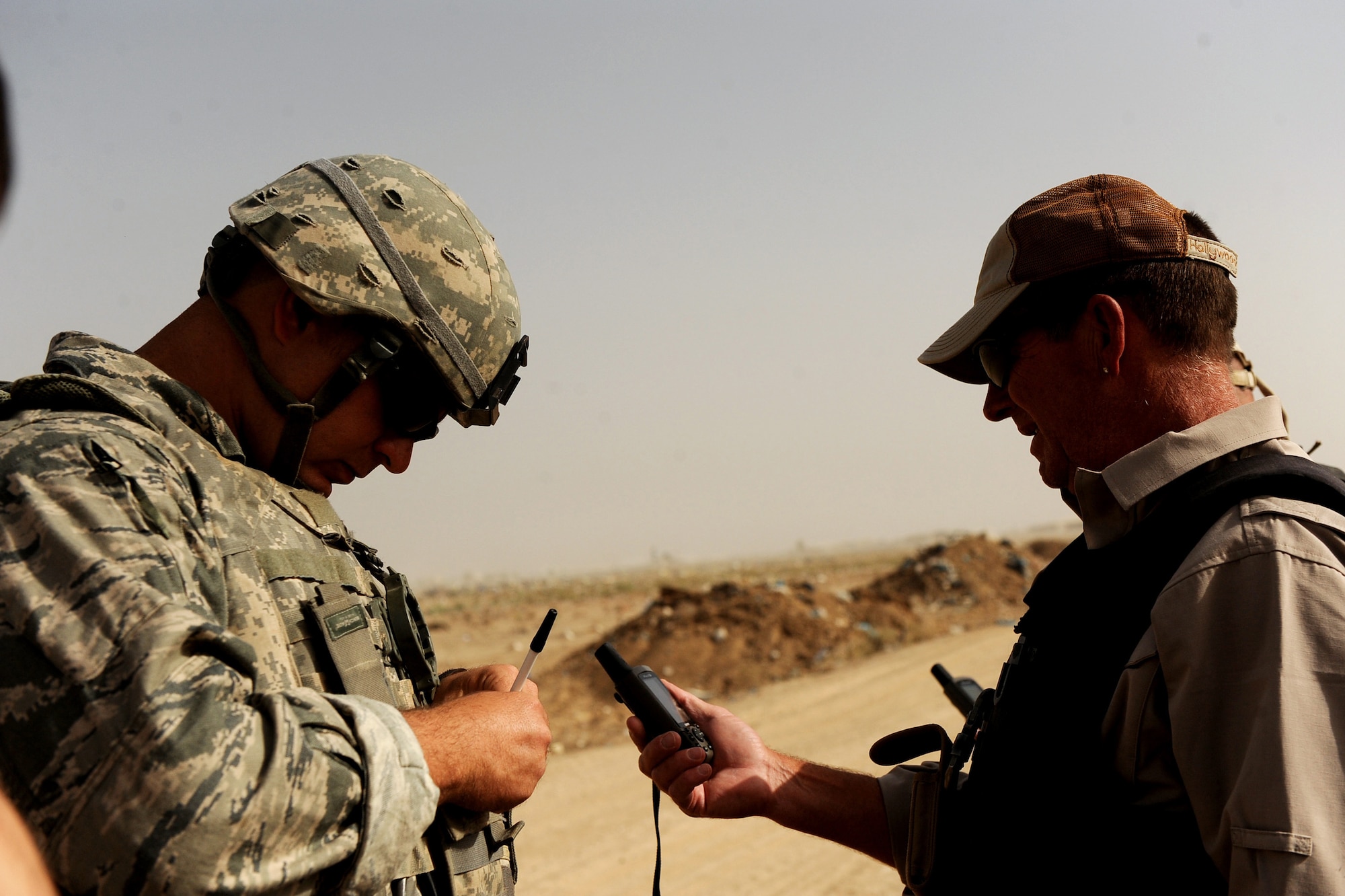 Tech. Sgt. David Niedzwiakdek, an explosive ordnance disposal technician assigned to the 755th Air Expeditionary Squadron, Operating Location-Bravo EOD, writes down the coordinates of the next site of M-42 bomblets to be destroyed, as Lee Thompson an Environmental Chemical Corporation contractor, reads them to him June 4, 2010, in Kandahar City, Afghanistan. (U.S. Air Force photo/ Staff Sgt. Manuel J. Martinez/released)