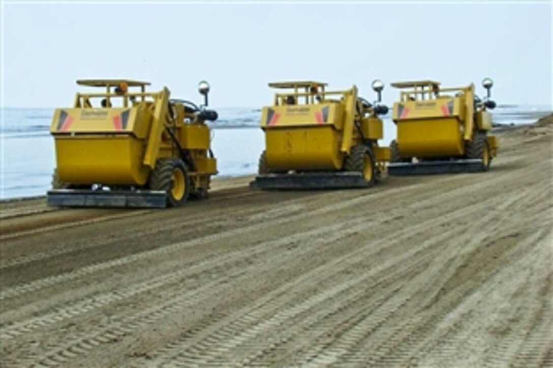 Crews aboard beach clean-up vehicles sift oil on the southeast Louisiana shoreline in Houma, La., June 10, 2010. Thousands of crews, including those from the U.S. military, are spread throughout the Gulf of Mexico area to battle the BP Deepwater Horizon oil spill.