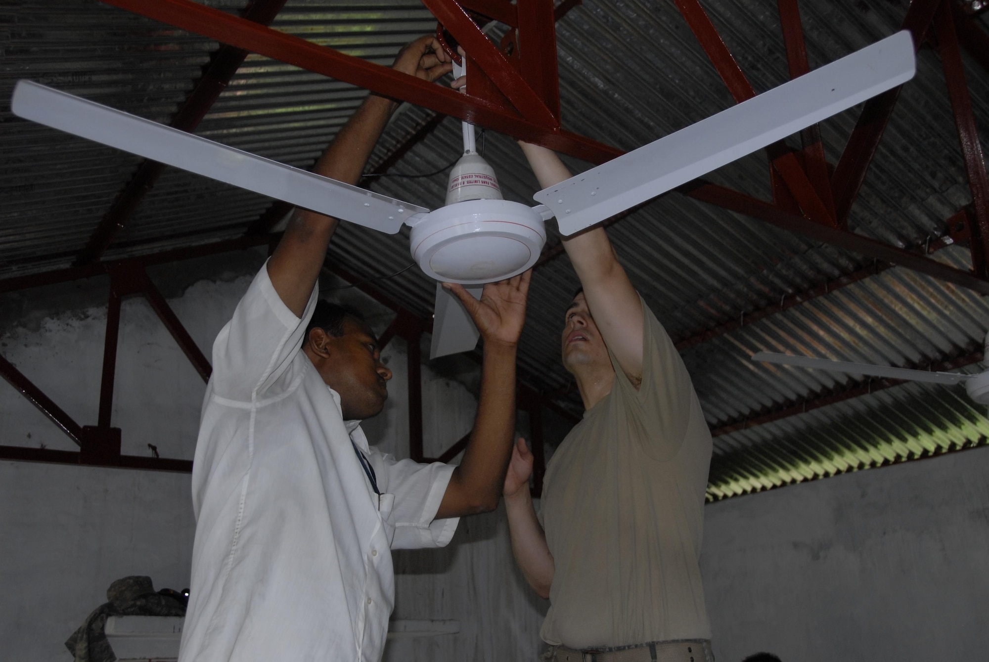 Airman 1st Class Rudy Alvarez, right, an electrical systems Airman from the 354th Civil Engineer Squadron at Eielson Air Force Base, Alaska, installs a ceiling fan at the Lauri High School and Primary School in Shyamkur Township near Jessore, Bangladesh, as part of Operation Pacific Angel on June 12, 2010. Operation Pacific Angel is a joint and combined humanitarian assistance operation conducted in the Pacific area of responsibility to support U.S. Pacific Command's capacity-building efforts. This humanitarian and civic assistance program is aimed at improving military civic cooperation between the United States and countries throughout the Asia-Pacific region. More than 55 U.S. military personnel are participating in civil and medical assistance programs with the help of the Bangladesh Air Force and local nongovernmental organizations. Medical care for Bangladesh citizens will include: primary care, women's health, dental and optometry. Several classrooms are being refurbished as part of the mission at the Lauri High School and Primary School. The operation is scheduled through June 16, 2010. (U.S. Air Force photo/1st Lt. Chris Hoyler) 