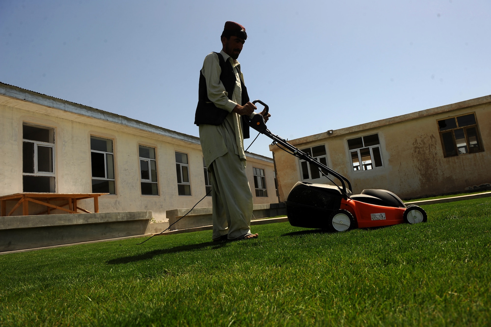 An Afghan man mows the lawn of the women's park at the Bibi Khala Girl's School May 31, 2010, in Qalat City, Afghanistan. The woman's park is a place where local women can mentor and commune with students. Previously, PRT Zabul aided the school by overseeing the building of a teaching garden that included landscaping and an irrigation system, a more than $300,000 project. (U.S. Air Force photo/Staff Sgt. Manuel J. Martinez/released) 

