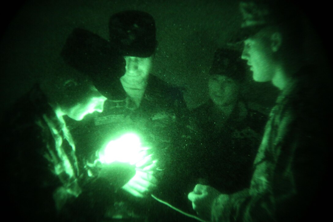 Lance Cpl. Joel Hindman (right), an assaultman with scout platoon, Headquarters and Service Company 1st Tank Battalion, explains the purpose of the “buzz saw” method to Ukrainian soldiers with the 30th Mechanized Infantry Bn., during a night vision training exercise at Babadag Training Area, Romania, June 14. The “buzz saw” is a checmical-light stick attached to a string and can be used to signal friendly forces.