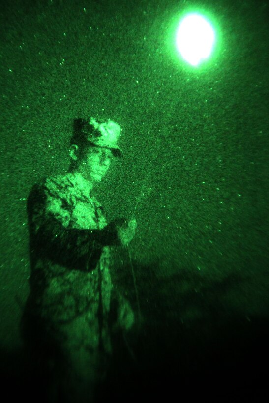 Lance Cpl. Mitch Sproull, a motor transportation operator with scout platoon, Headquarters and Service Company, 1st Tank Battalion, demonstrates the “buzz saw” method to Ukrainian and Romanian Army soldiers during a night vision training exercise at Babadag Training Area, Romania, June 14. The “buzz saw” is a checmical-light stick attached to a string and can be used to signal friendly forces.