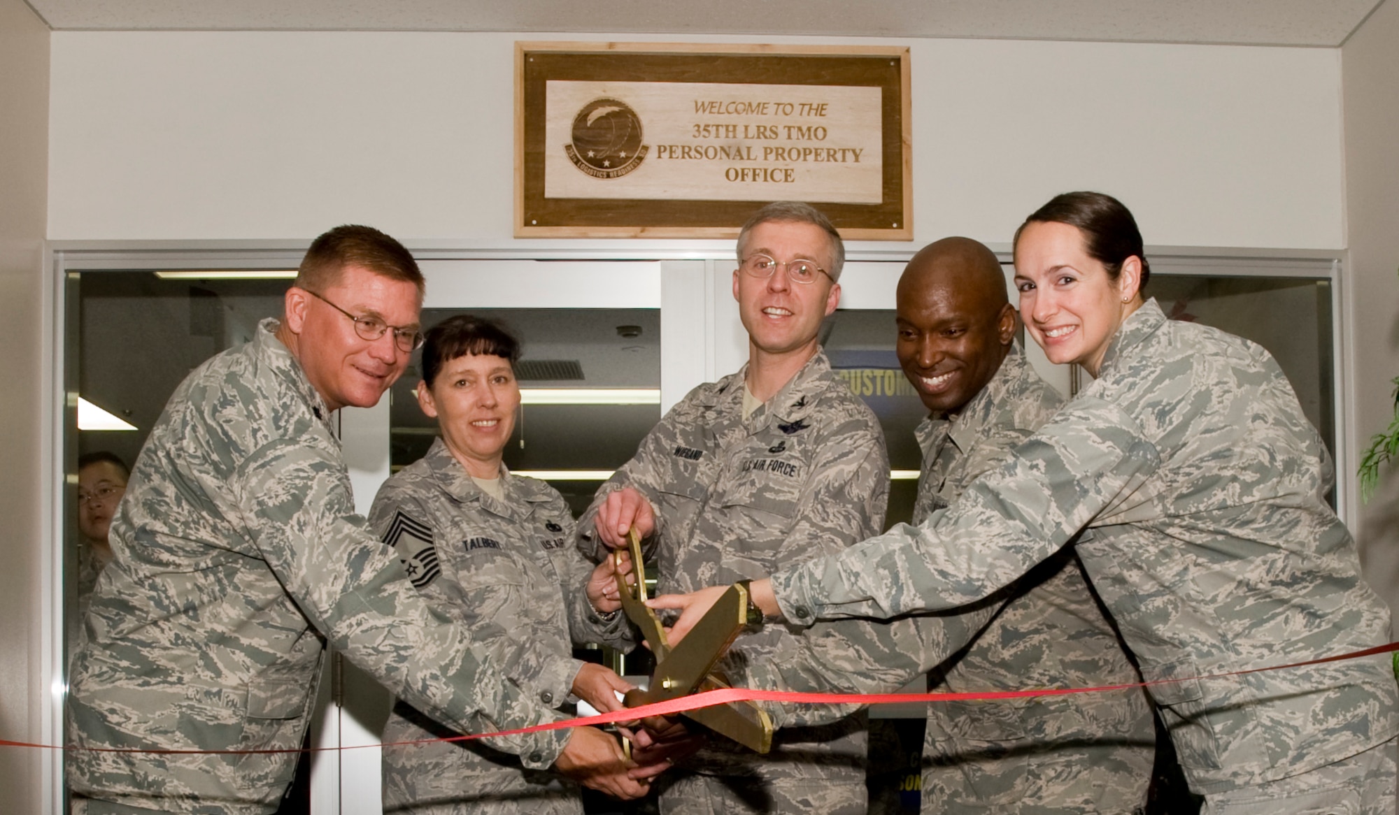 MISAWA AIR BASE, Japan -- Col. David Wiegand, 35th Mission Support Group commander, along with Lt. Col. Gary Jackson, Chief Master Sgt. Suzanne Talbert, Master Sgt. Travis Griffin and Capt. Heather McDaniel, cuts the ceremonial ribbon during the grand reopening of the 35th Logistics Readiness Squadron Traffic Management Office Personal Property Section June 15. Personal Property's new location is in the Torii Building Room 1100, adjacent to the 35th Civil Engineer Squadron Housing Office. (U.S. Air Force photo/Senior Airman Jamal D. Sutter)