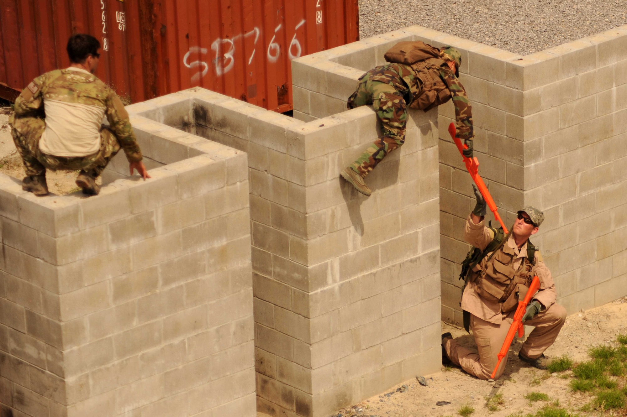 A Hurlburt Airman participating in Survival, Evasion, Resistance, and Escape training, hands her training M-16 rifle to another Airman as she climbs over a wall as a SERE specialist looks on during combat skills training at an undisclosed location within the Eglin Range, Fla., May 13, 2010.  SERE specialists are able to utilize the multitude of resources and experiences from their fellow 1st Special Operations Support Squadron Range Support flight to prepare Airmen for situations that may happen in combat. (DoD photo by U.S. Air Force Senior Airman Matthew Loken/Released)