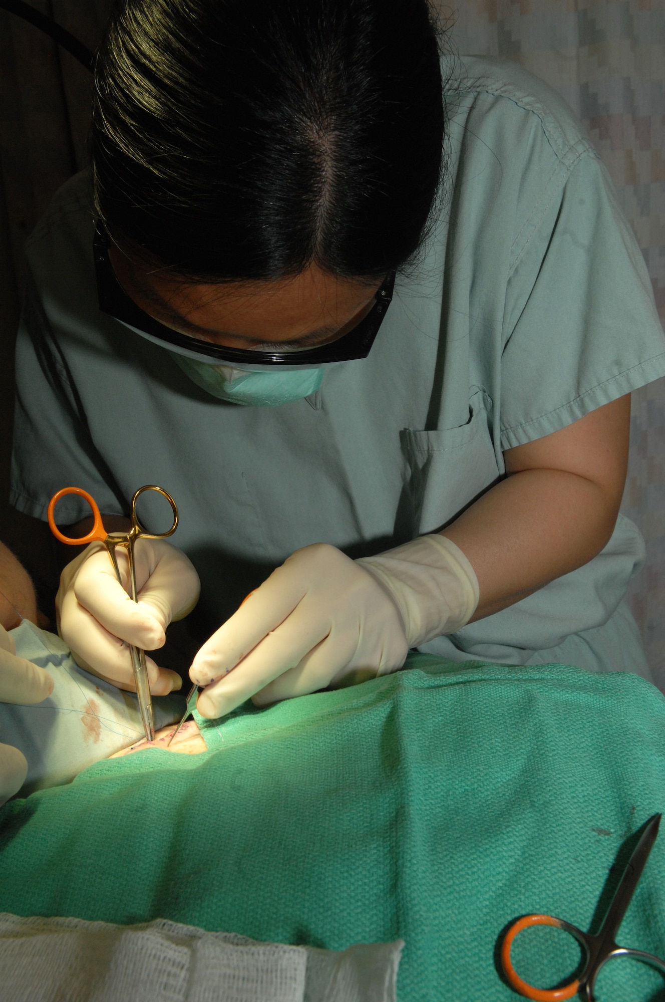 ELMENDORF AIR FORCE BASE, Alaska --Major Joy Wu, 3rd Wing Medical Group, dermatology chief stitches a patient after surgery to remove a section of skin with basal cell skin cancer. (Air Force photo by Airman 1st Class Jack Sanders)