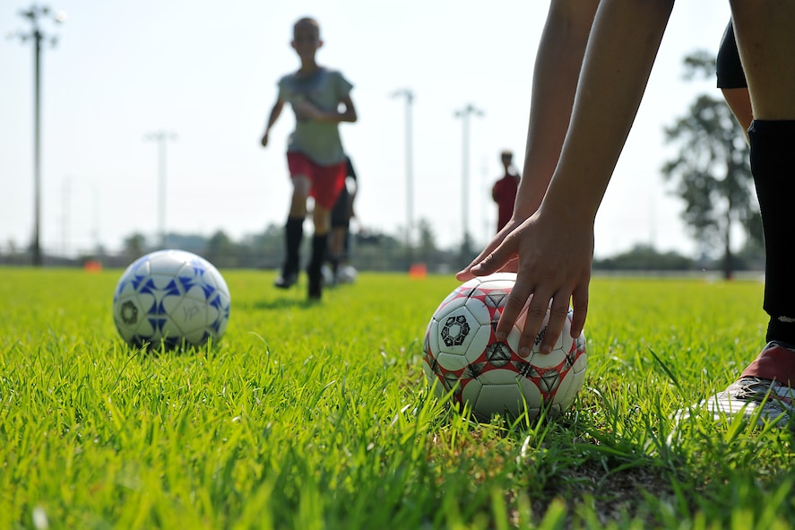 MOODY AIR FORCE BASE, Ga. -- A child from the Youth Center reaches down to pick up a soccer ball during a Major League Soccer camp here June 11. The camp consisted of performing specific drill designed to develop soccer skills for age two to 12 years old. (U.S. Air Force photo by Airman 1st Class Joshua Green/RELEASED)