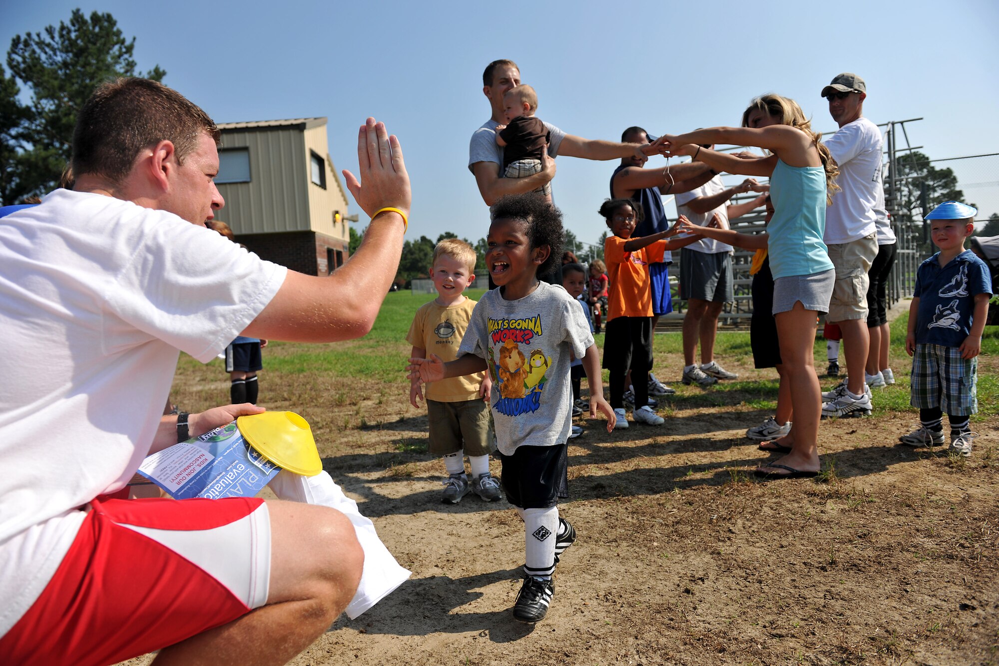 MOODY AIR FORCE BASE, Ga. -- Joseph Williams, child of Staff Sgt. Joseph Williams, 23rd Equipment Maintenance Squadron A-10 phase craftsmen, gives a high five to Jamie Bell, coach of Chicago fire, at the end of a Major League Soccer camp here June 11. The camp is held annually and helps youth, age two to 12 years old, develop soccer skills. (U.S. Air Force photo by Airman 1st Class Joshua Green/RELEASED)