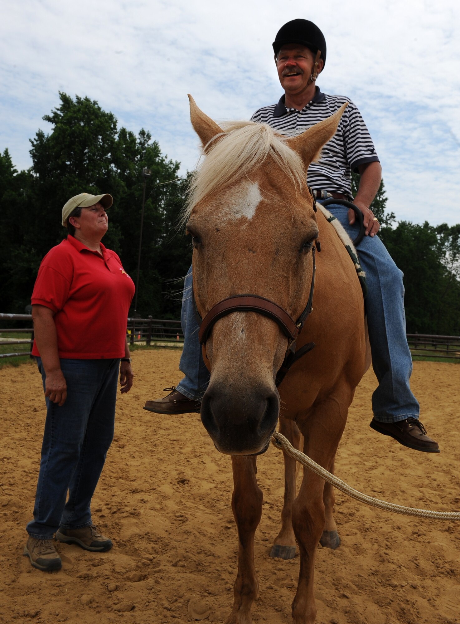 LANGLEY AIR FORCE BASE, Va. - Lee Moore, an instructor from the North American Riding for Handicap Association assists Terry “Tom” Steele during a Horses Helping Heroes therapy session June 3. Therapy ranges from simply sitting atop the horse to walking, trotting and brushing the horse. (U.S. Air Force photo/Senior Airman Gul Crockett)