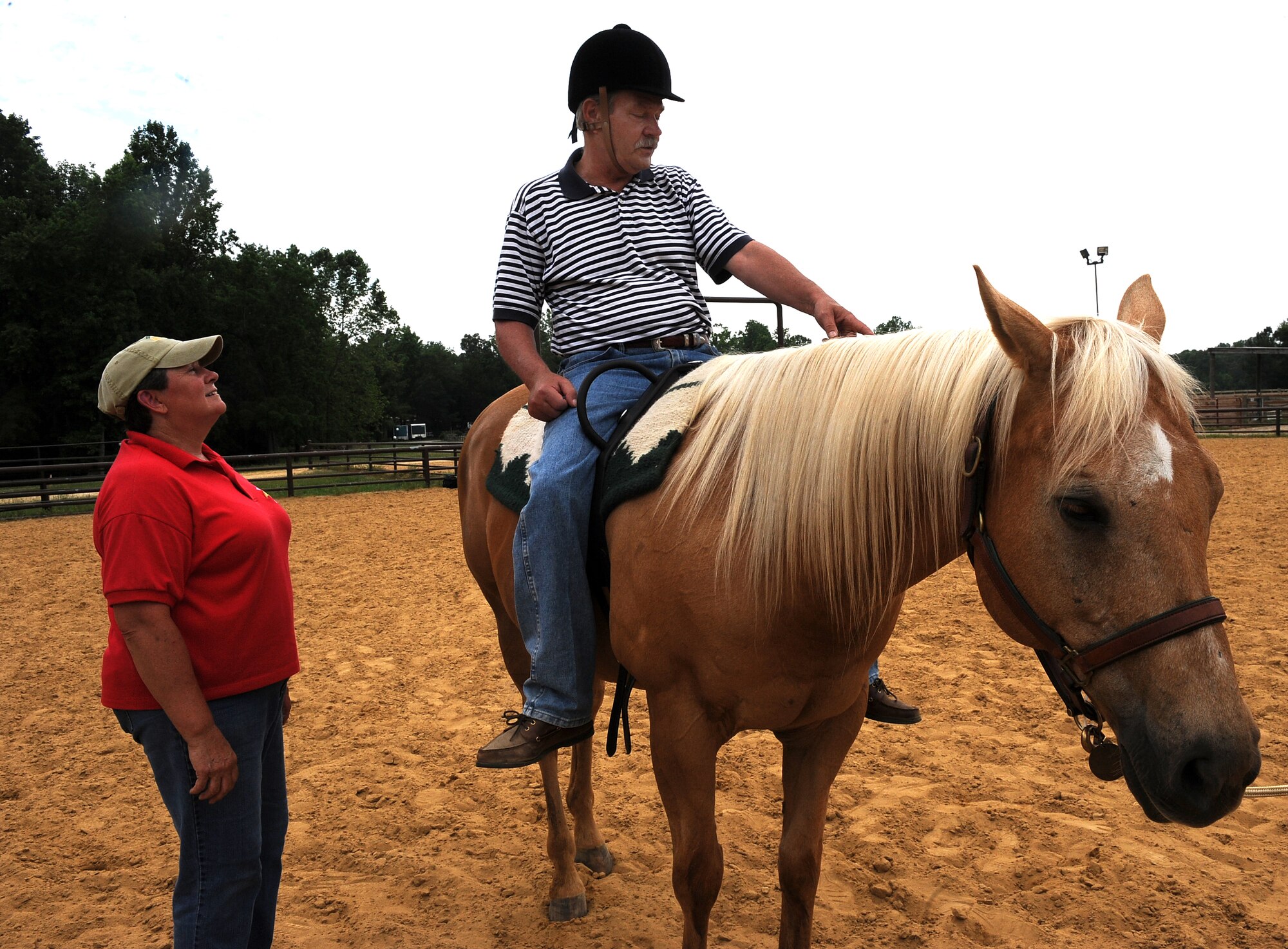 LANGLEY AIR FORCE BASE, Va. -- Lee Moore, an instructor from the North American Riding for Handicap Association, assists Terry “Tom” Steele during a Horses Helping Heroes therapy session June 3. Therapy ranges from simply sitting atop the horse to walking, trotting and brushing the horse. (U.S. Air Force photo/Senior Airman Gul Crockett)