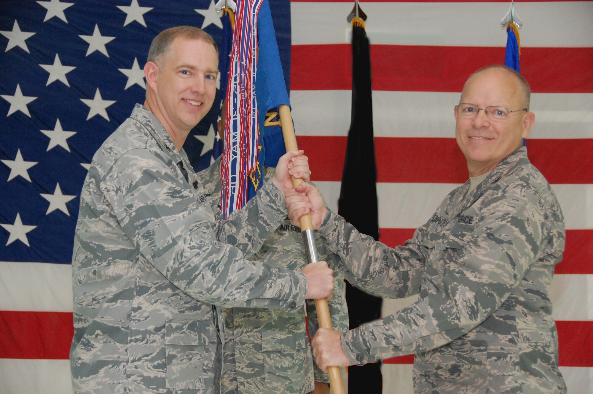From left, U.S. Air Force Col. John R. Gordy II, 386th Air Expeditionary Wing commander, passes the 386th Expeditionary Maintenance Group guidon to Col. Ricky Thompson, 386th EMXG commander, after taking command of the unit in a ceremony June 14, 2010 at an air base in Southwest Asia. (U.S. Air Force photo by Staff Sgt. Lakisha A. Croley/Released)