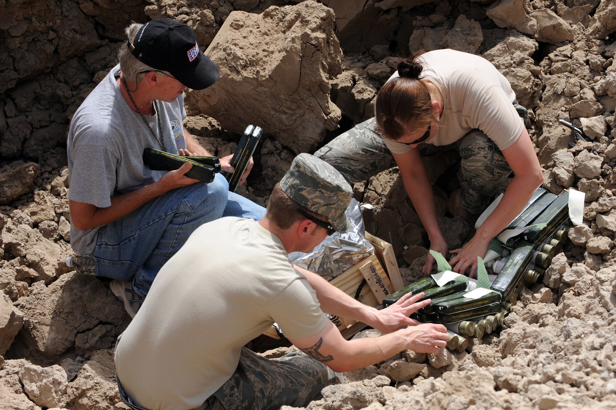Senior Airman Nicole Nellist, 447th Expeditionary Civil Engineer Squadron, explosive ordinance technician, deployed from Dover Air Force Base, Delaware, Frank Skinson, Sather Air Base USO, and SrA. Adrian Contreras, 447th Expeditionary Communications Squadron, custodian of postal effects, lay C4 explosives over 40mm grenades June 12, 2010 at Sather Air Base, Iraq. Mr. Skinson, and Airman Contreras were assisting EOD to destroy unserviceable munitions. (U.S. Air Force photo by Senior Airman Perry Aston) (Released)