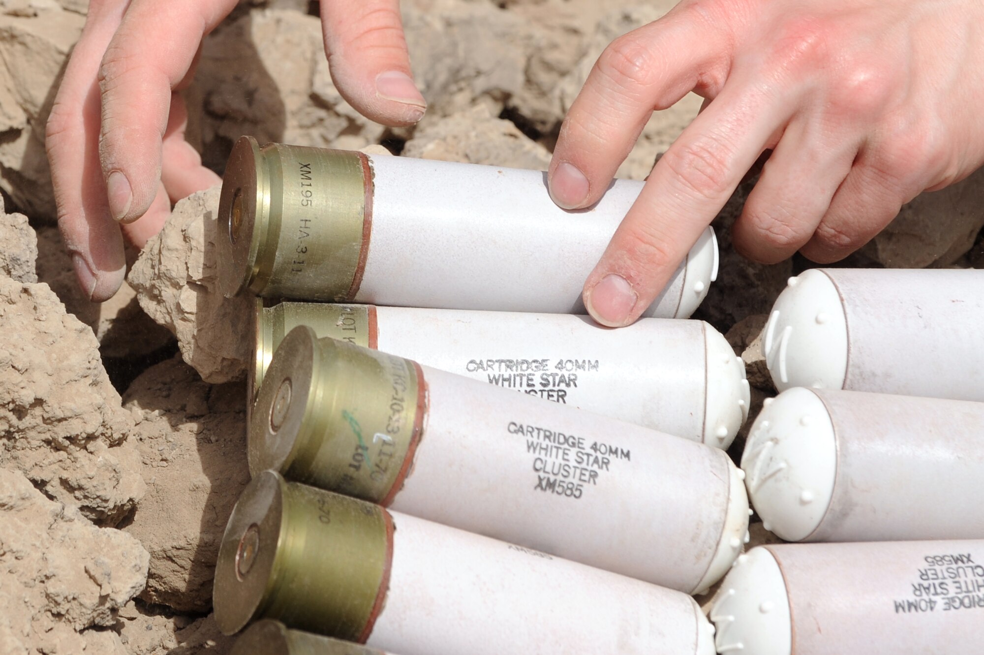 SrA. Adrian Contreras, 447th Expeditionary Communications Squadron, custodian of postal effects, lays 40mm grenades to be destroyed June 12, 2010 at Sather Air Base, Iraq. Mr. Skinson, and Airman Contreras were assisting EOD to destroy unserviceable munitions. (U.S. Air Force photo by Senior Airman Perry Aston) (Released)