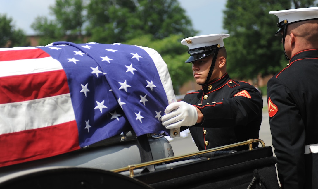 Lance Cpl. Jermain Streeter draps the U.S. flag over the casket of retired Col. John S. Hudson at Arlington National Cemetery June 14. Streeter is a Marine Corps body bearer stationed at Marine Barracks Washington. Body bearers are responsible for carrying the remains of fallen Marines to their final resting place. (Photo by Cpl. Bobby J. Yarbrough)