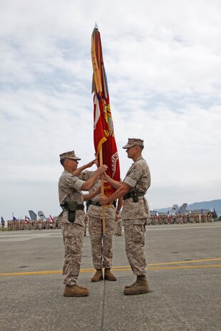 Lt. Col. Charles A. Redden (left) accepts the colors from Lt. Col. Jonathan O. Gackle (right) at the Marine Aviation Logistics Squadron 12 change-of-command ceremony at the Marine All Weather Fighter Attack Squadron 242 hangar Monday. The transfer of colors signifies the passing of command from the outgoing commanding officer to the oncoming commanding officer.