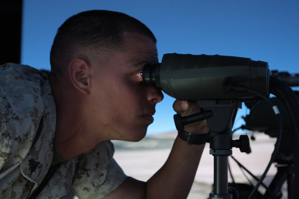 Corporal Omar Curbelo, a light armored vehicle crewman with Company E, 3rd Light Armored Reconnaissance Battalion, looks through the Vector 21B binoculars to find the simulated targets at the Supporting Arms Virtual Trainer June 15. The trainer gives Marines a chance to call in mortar, artillery and air strikes against simulated enemy positions.