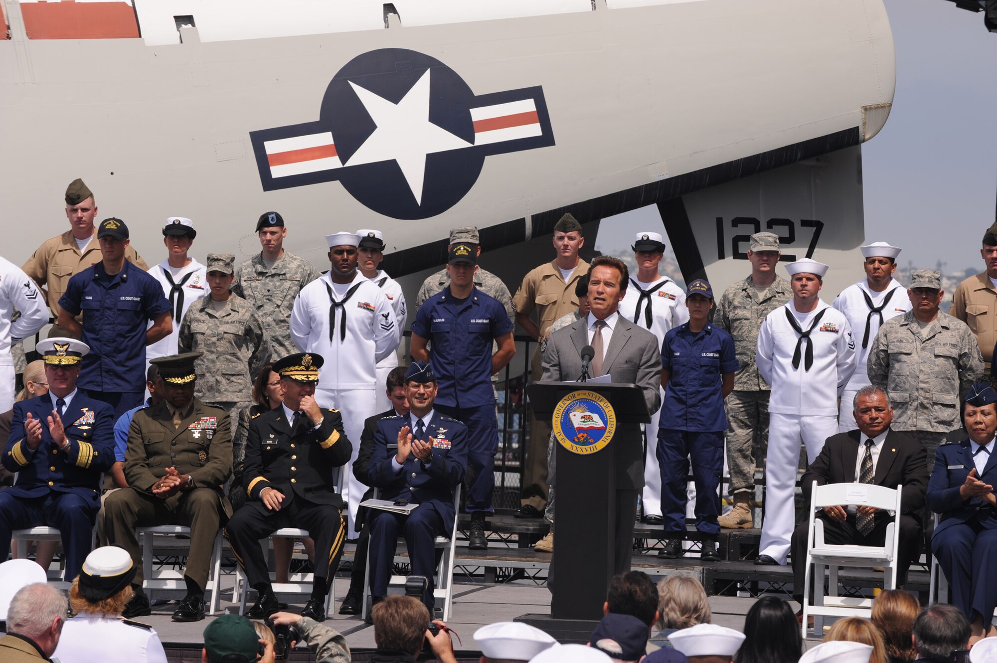 California Governor Arnold Schwarzenegger (center) delivers a speech surrounded by Lt. Gen. John “Tom” Sheridan (left), Space and Missile Systems Center commander, other flag officers and service members, and state cabinet members at the Operation Welcome Home kick-off aboard the U.S.S. Midway in San Diego, June 3.  The mission of California’s Operation Welcome Home is to directly connect with the 30,000 veterans annually returning to California so they can access the benefits they have earned and the services that can help them transition successfully from military service to civilian life.  Governor Schwarzenegger has targeted $20 million to hire 325 people to directly reach out and connect with combat veterans.   (Photo by Joe Juarez)  