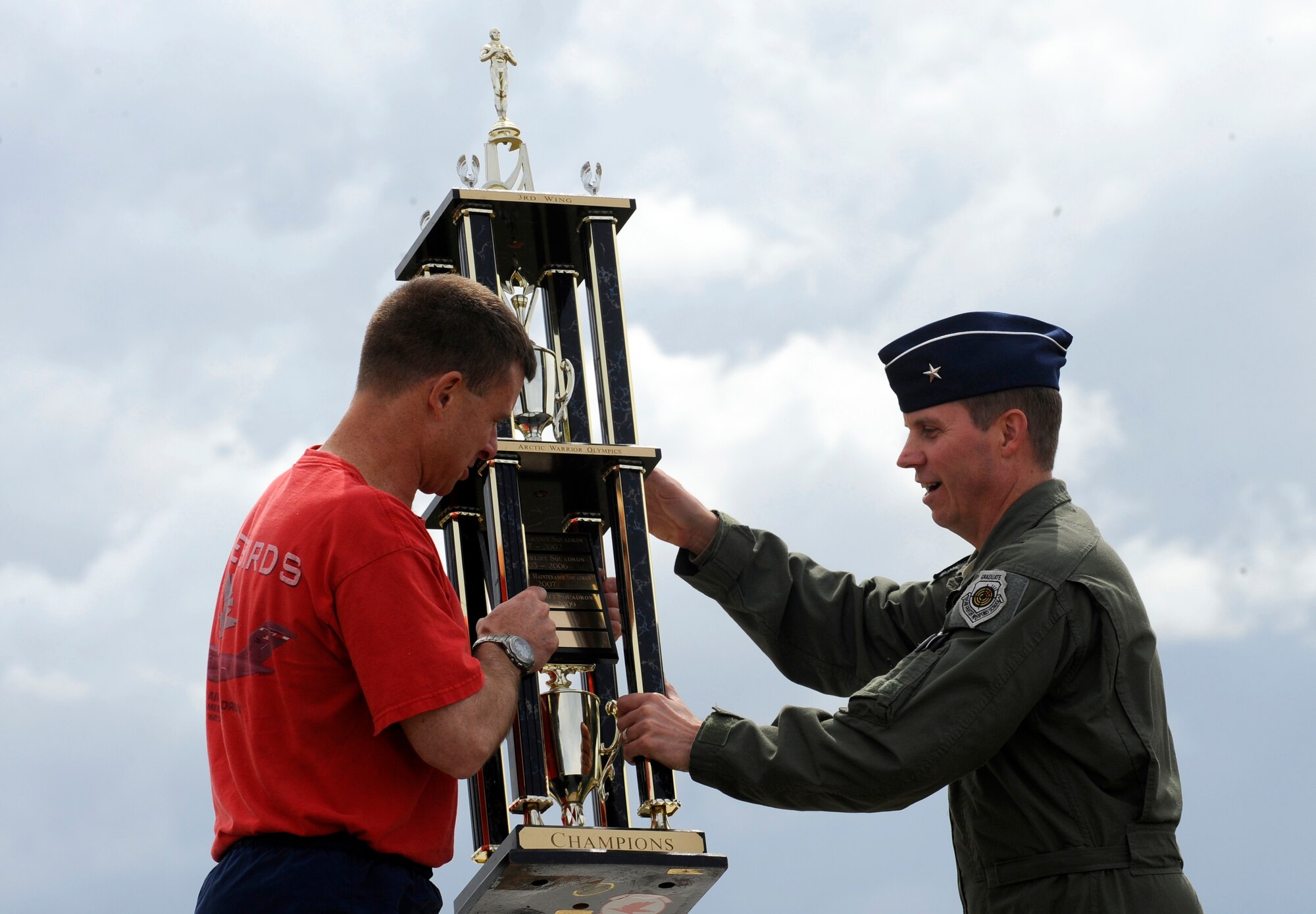 Lt. Col. Andy Hird, 517th Airlift Squadron commander, accepts the 1st place Arctic Warrior Olympics trophy from Brig. Gen. Thomas Bergeson, 3rd Wing commander, on behalf of his squadron, June 11. This is the seventh time in ten years the squadron has won the trophy. (U.S. Air Force photo/Staff Sgt. Brian Ferguson)