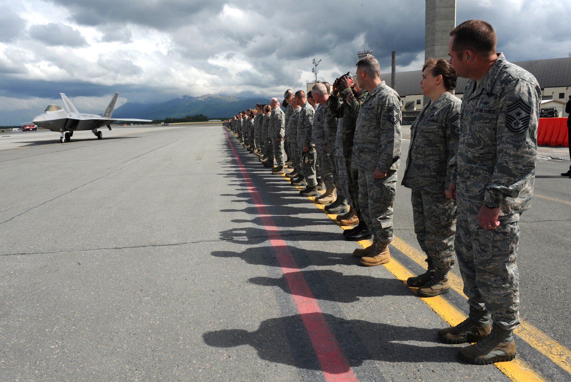 Airmen from the 3rd Wing prepare to salute Brig. Gen. Thomas Bergeson, 3rd Wing commander, as he taxis in an F-22 Raptor June 10 after his fini-flight. (Air Force photo by Senior Airman Cynthia Spalding)